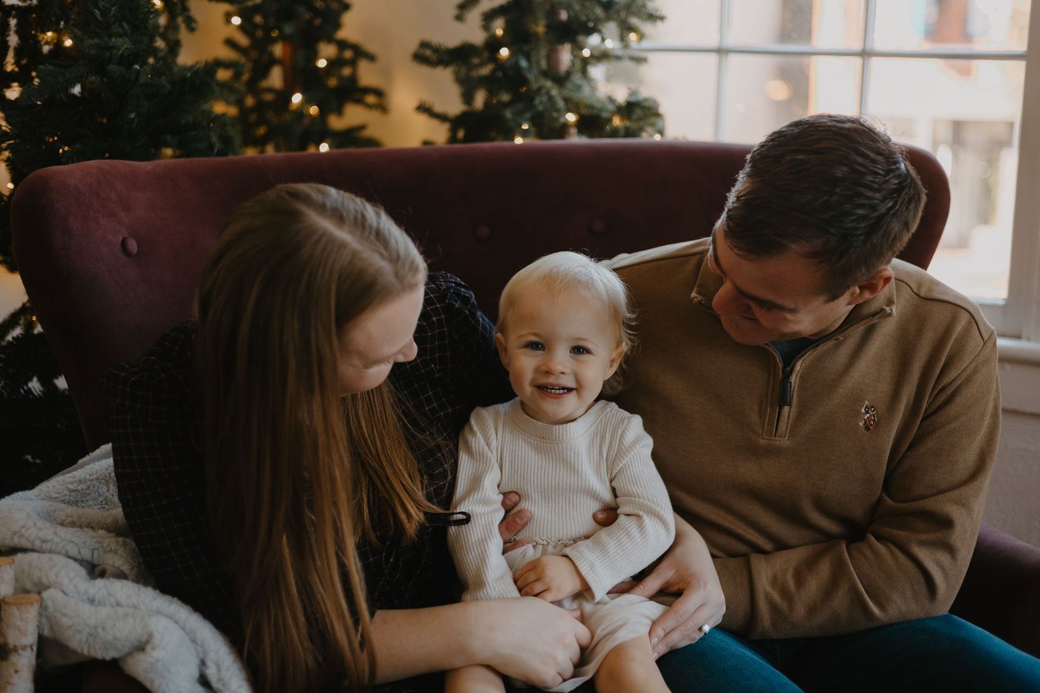 A family sits together near a decorated Christmas tree in their home.
