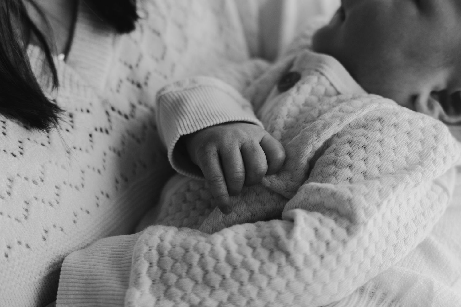 Close-up of infant wrapped in textured white knit blanket.