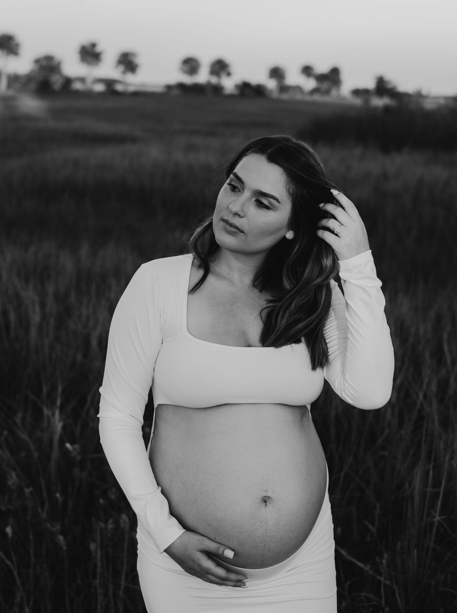 Black and white maternity photo showing a pregnant belly in a natural outdoor setting.