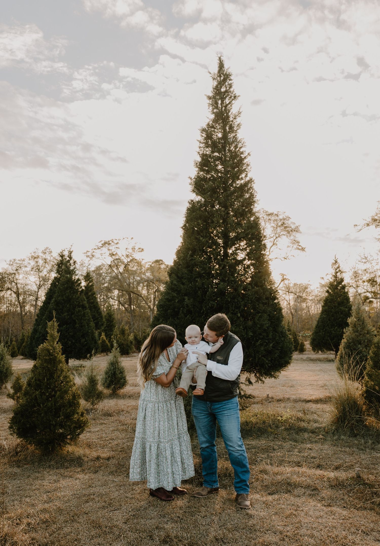 A couple dances among evergreen trees at a Christmas tree farm.