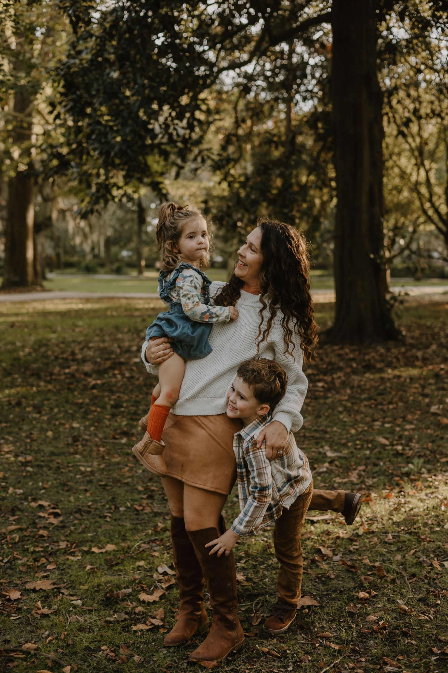 Playful family interactions captured in wooded park during fall season.