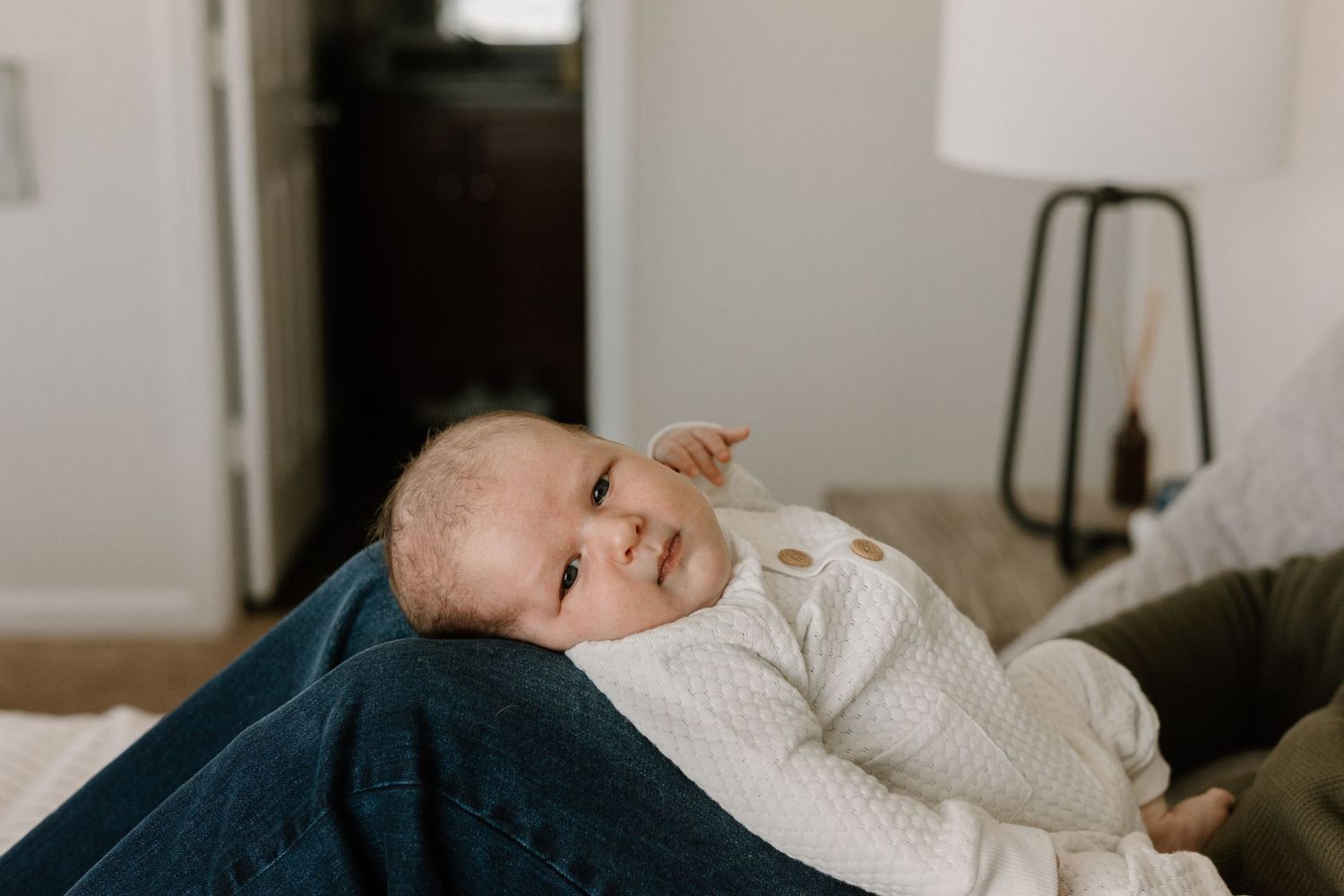 Newborn baby sleeping peacefully in white bedding at home.