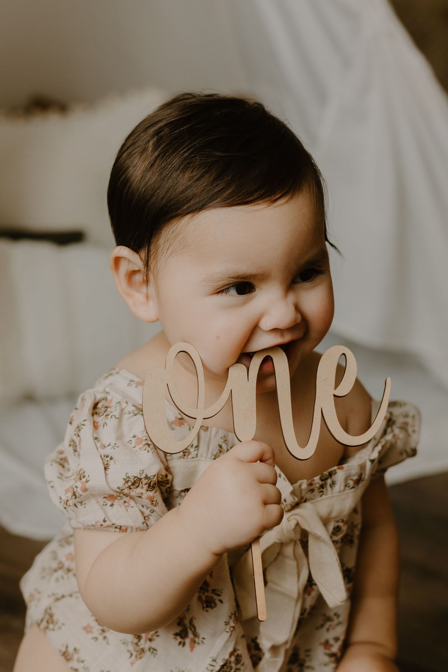 Baby holding wooden letters in soft indoor portrait session.