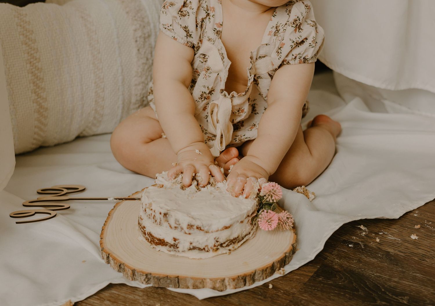 Baby playing with wooden decorations on rustic surface during photo session.