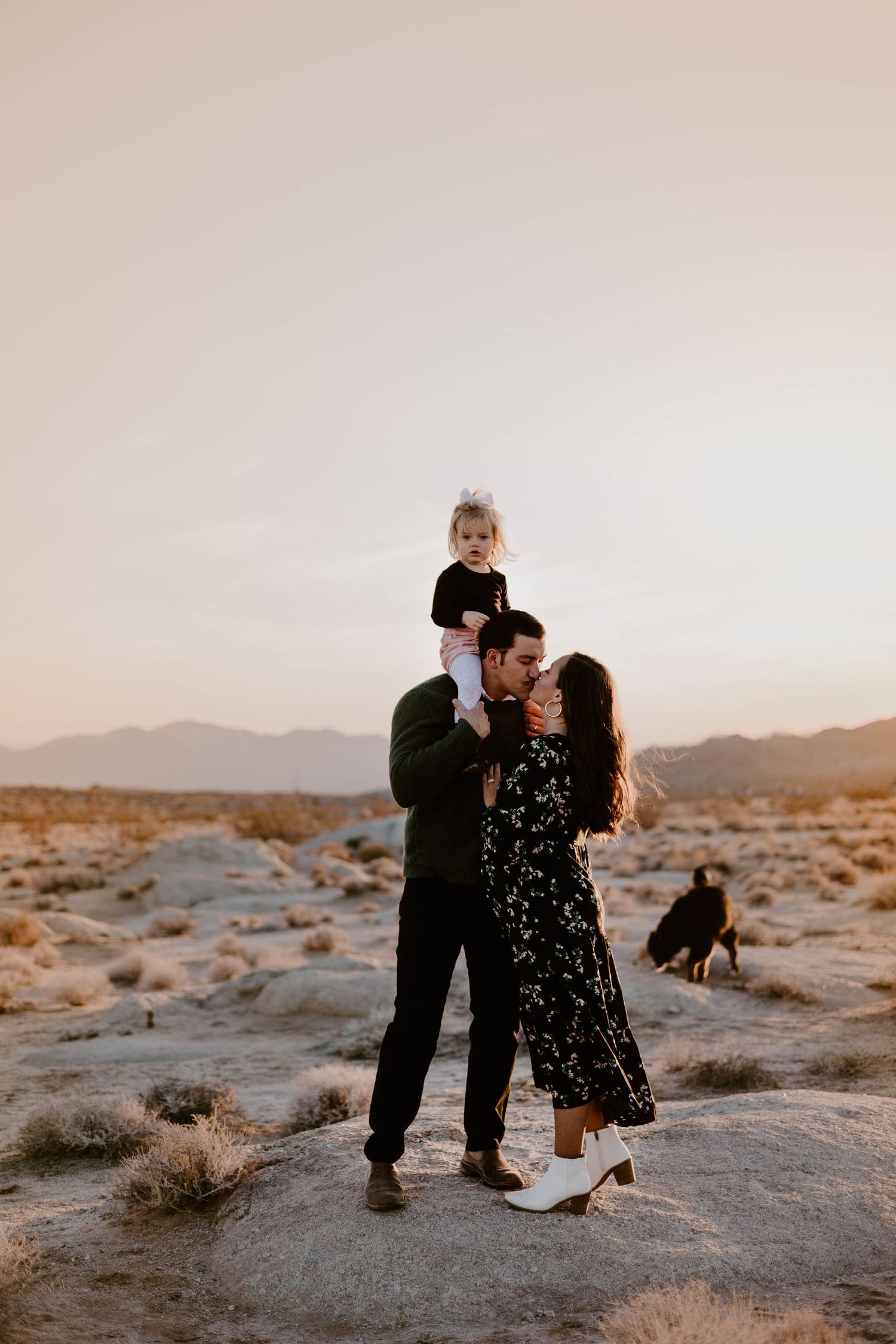 Family maternity photos in desert landscape during golden hour.