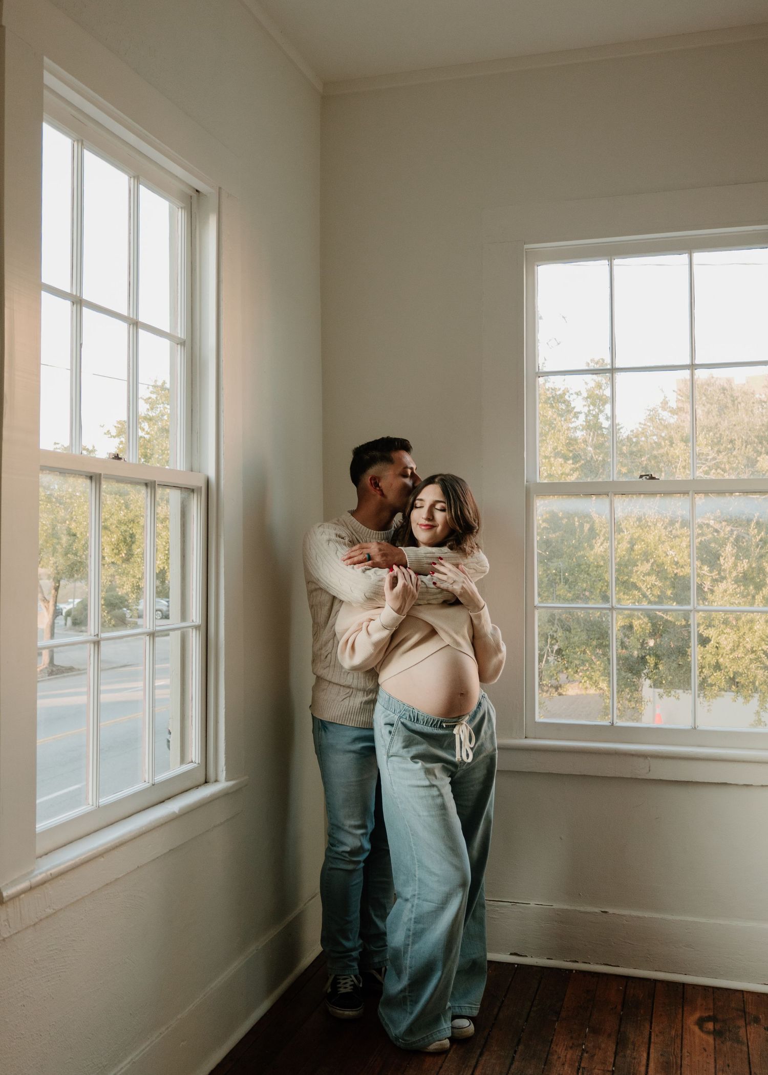 Series of intimate poses between couple in bright indoor setting with large windows.