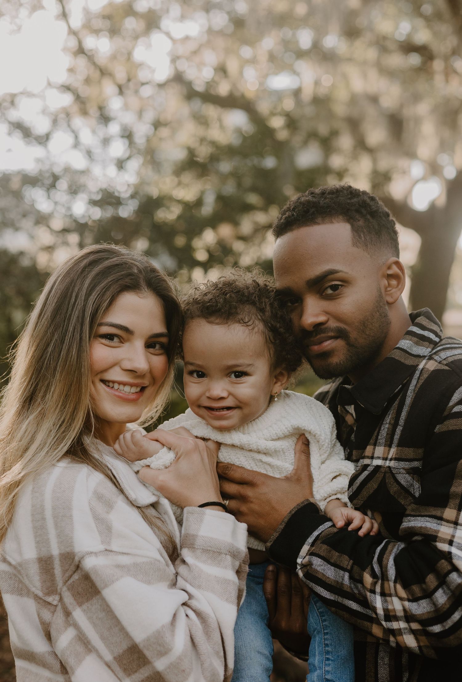 Family sharing a tender moment together outdoors in warm lighting.