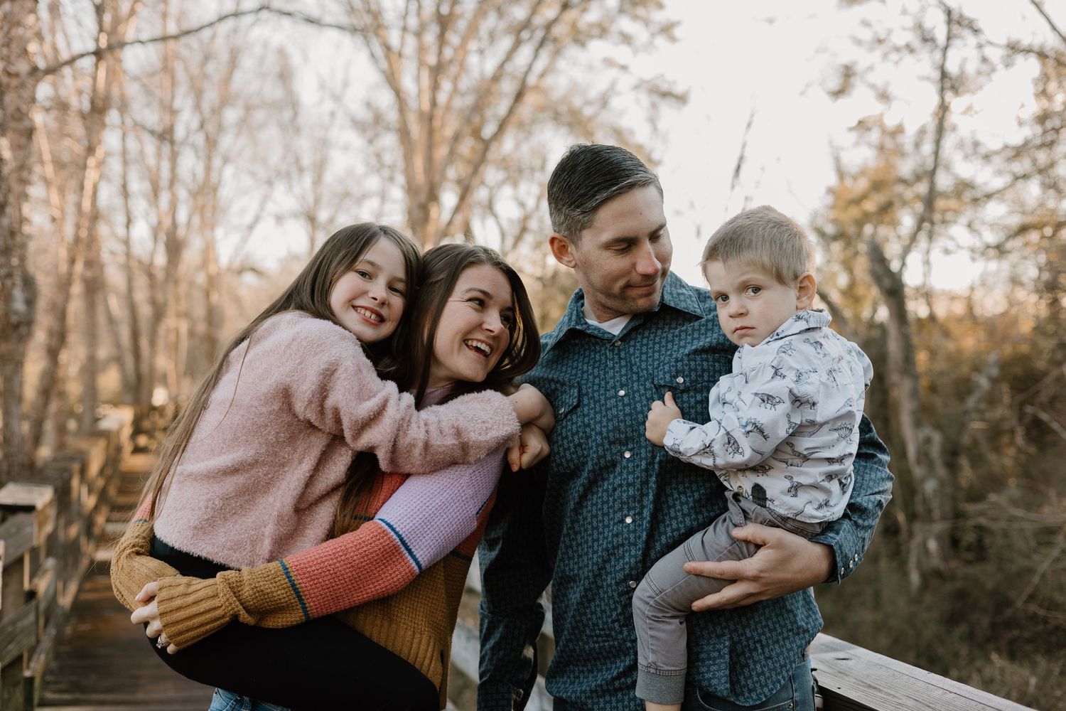 Family shares tender moments together during autumn outdoor photo session.