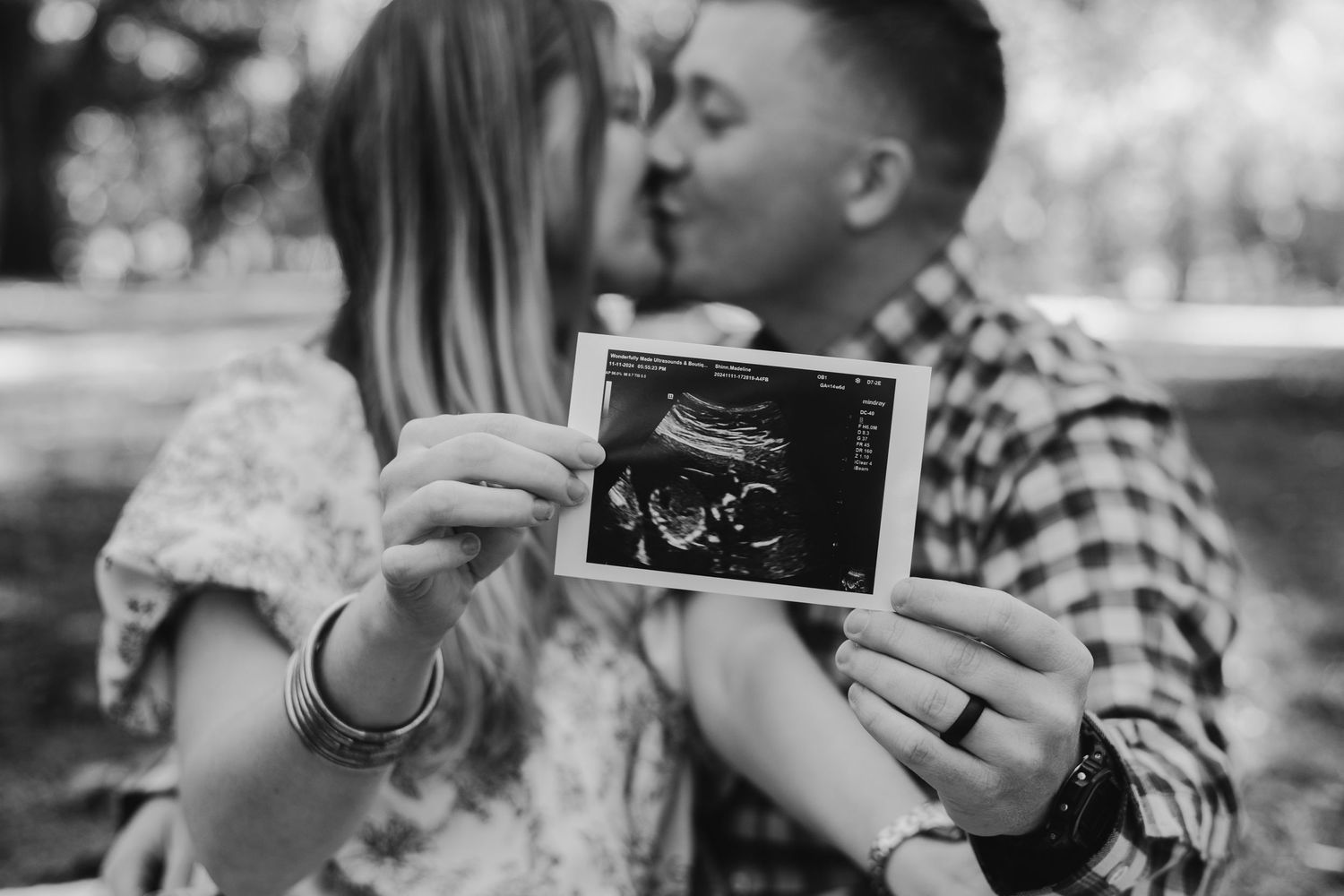 Black and white photo series of couple holding ultrasound photos and embracing.