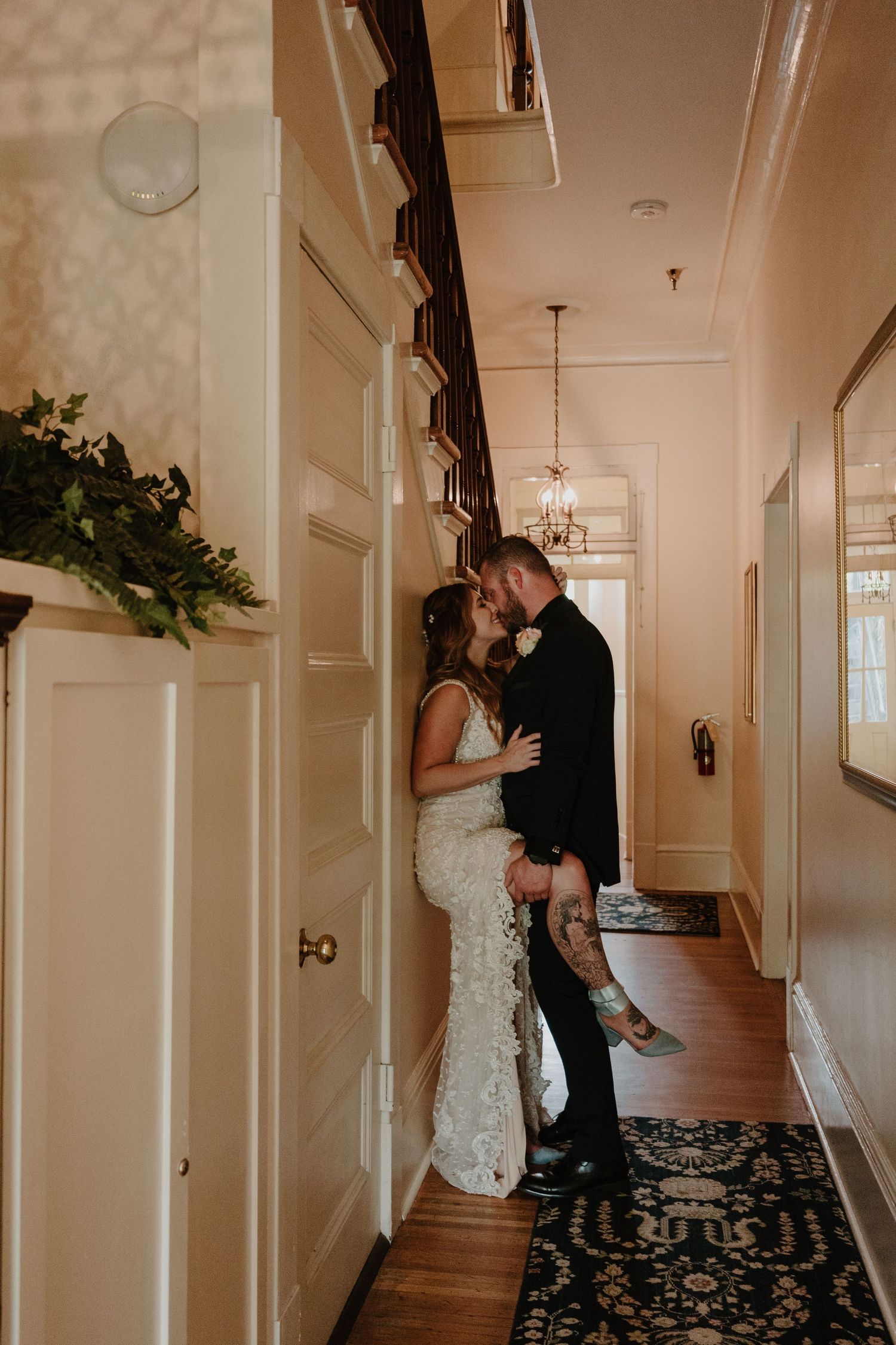 A couple shares intimate moments in an elegant hallway with patterned carpet and white walls.
