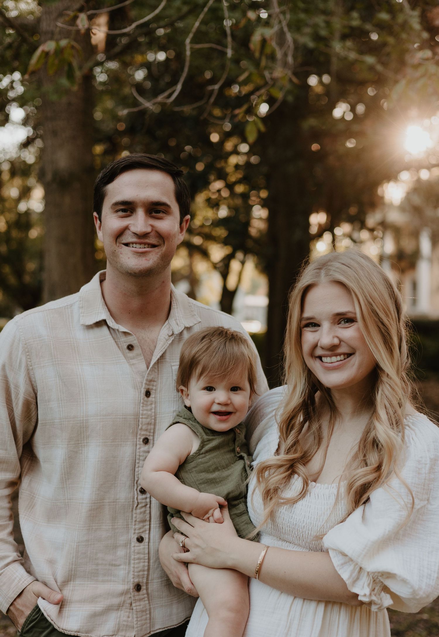 Family photo session in coordinated neutral outfits against a natural outdoor setting.