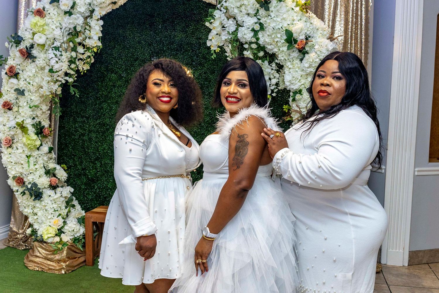 Elegant white-themed photo session with floral wall backdrop and formal attire.