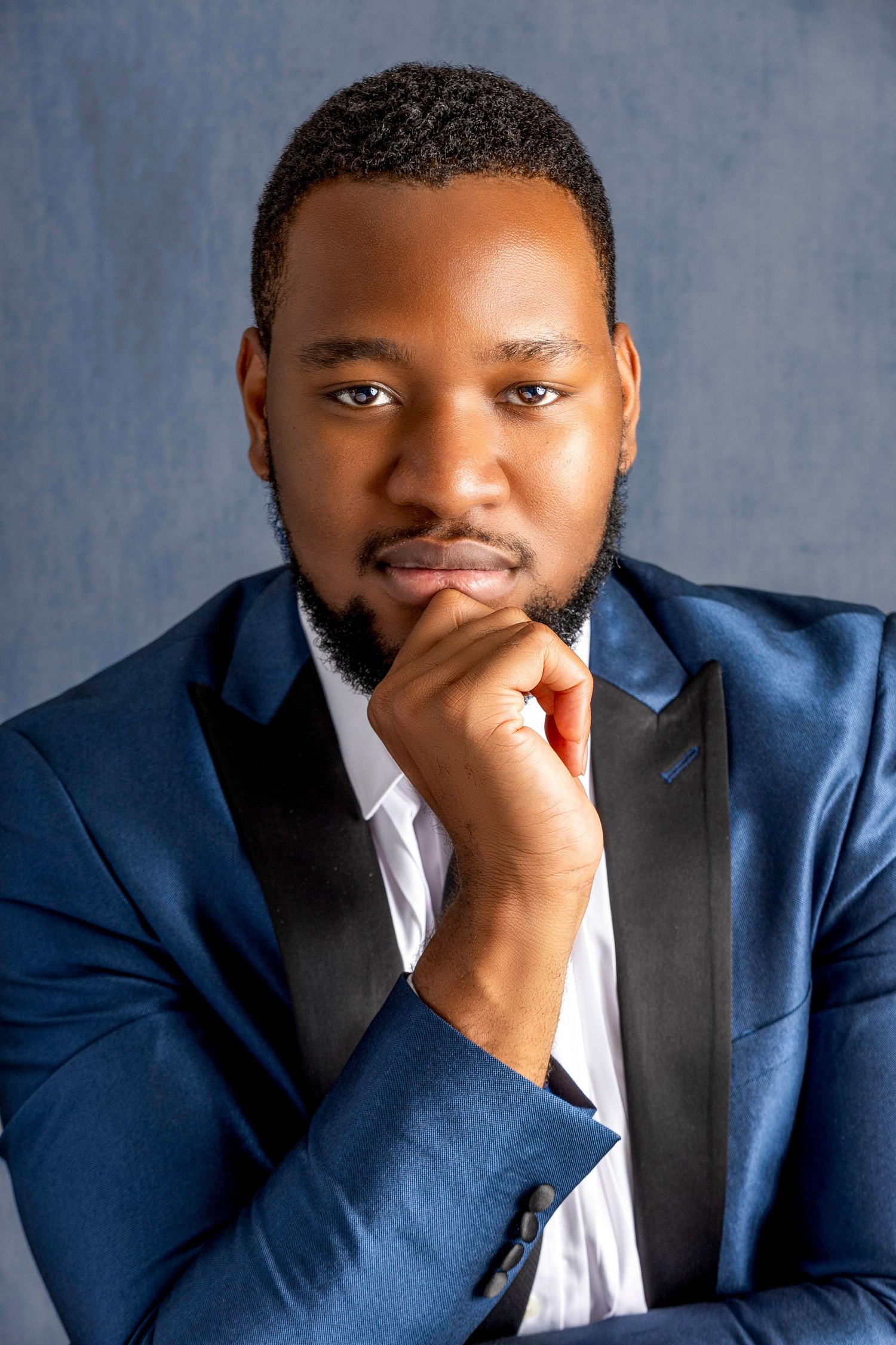 Professional portrait series showing expressions and emotions in a navy blue suit against a blue background.