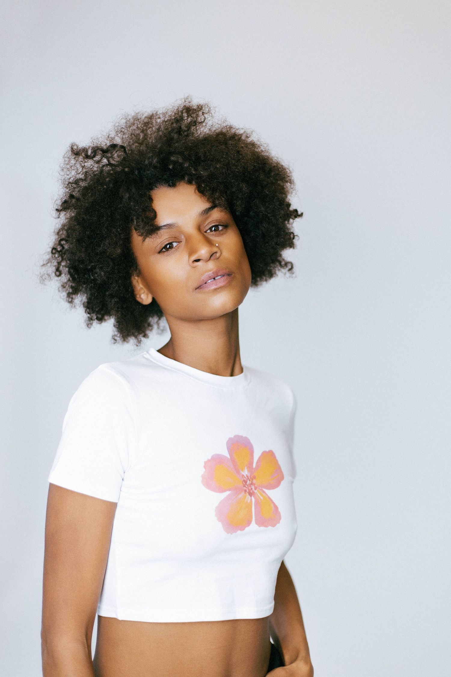 Four fashion photos show a model wearing a white crop top with a pink floral design against a light background.