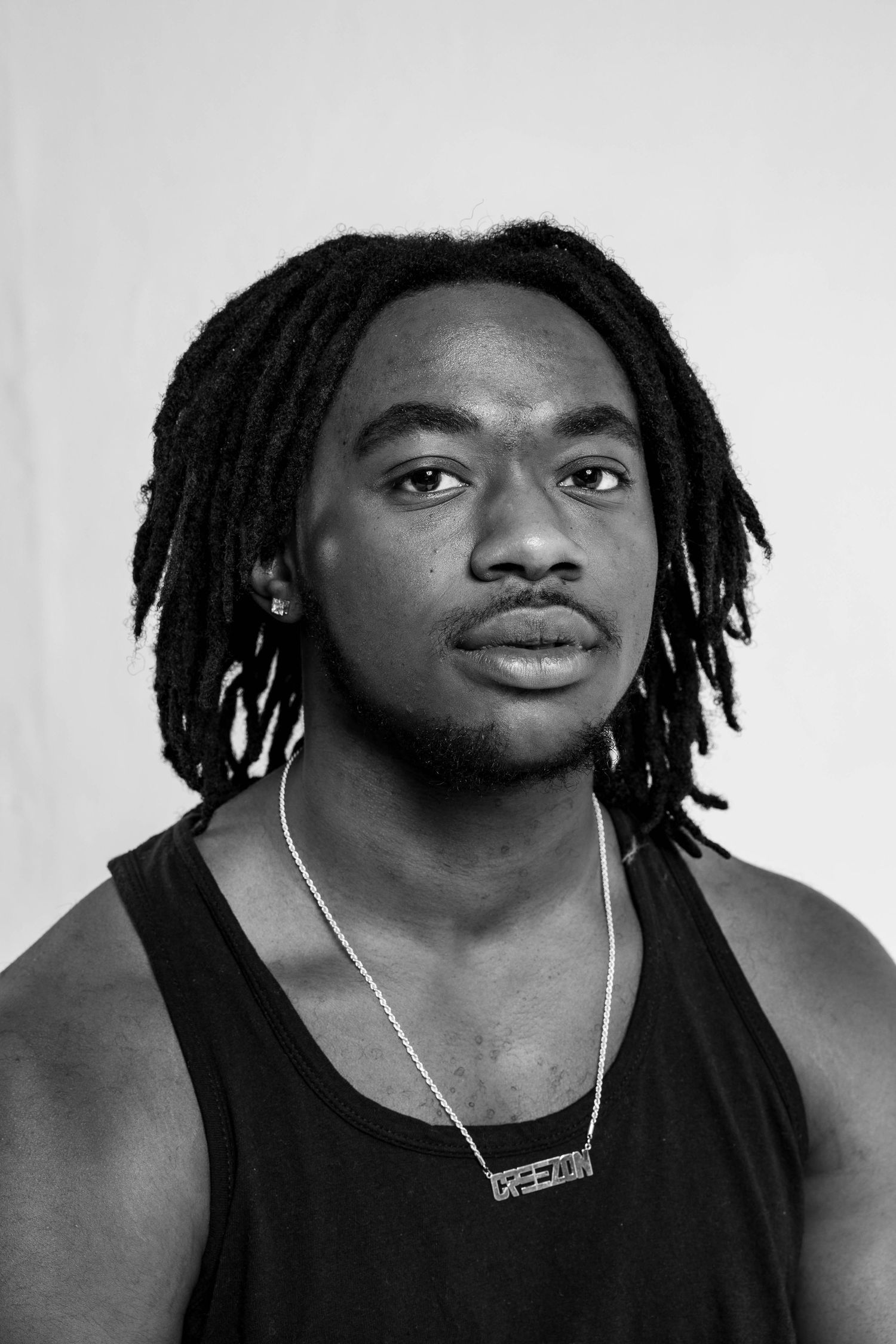 Black and white portrait series showing dreadlocks and silver necklace against light background.
