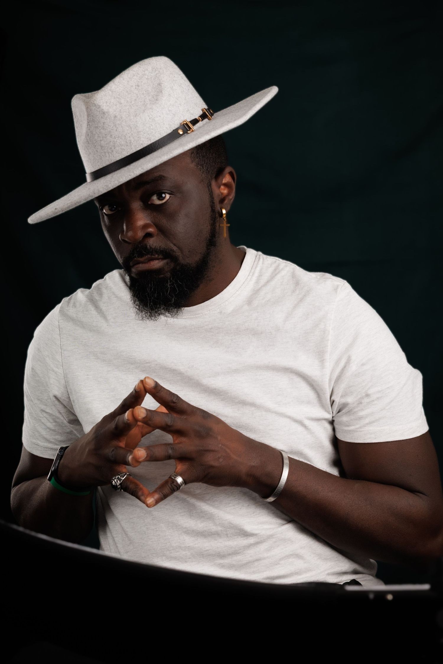 Dramatic portraits of someone in a white hat and t-shirt against a dark background.