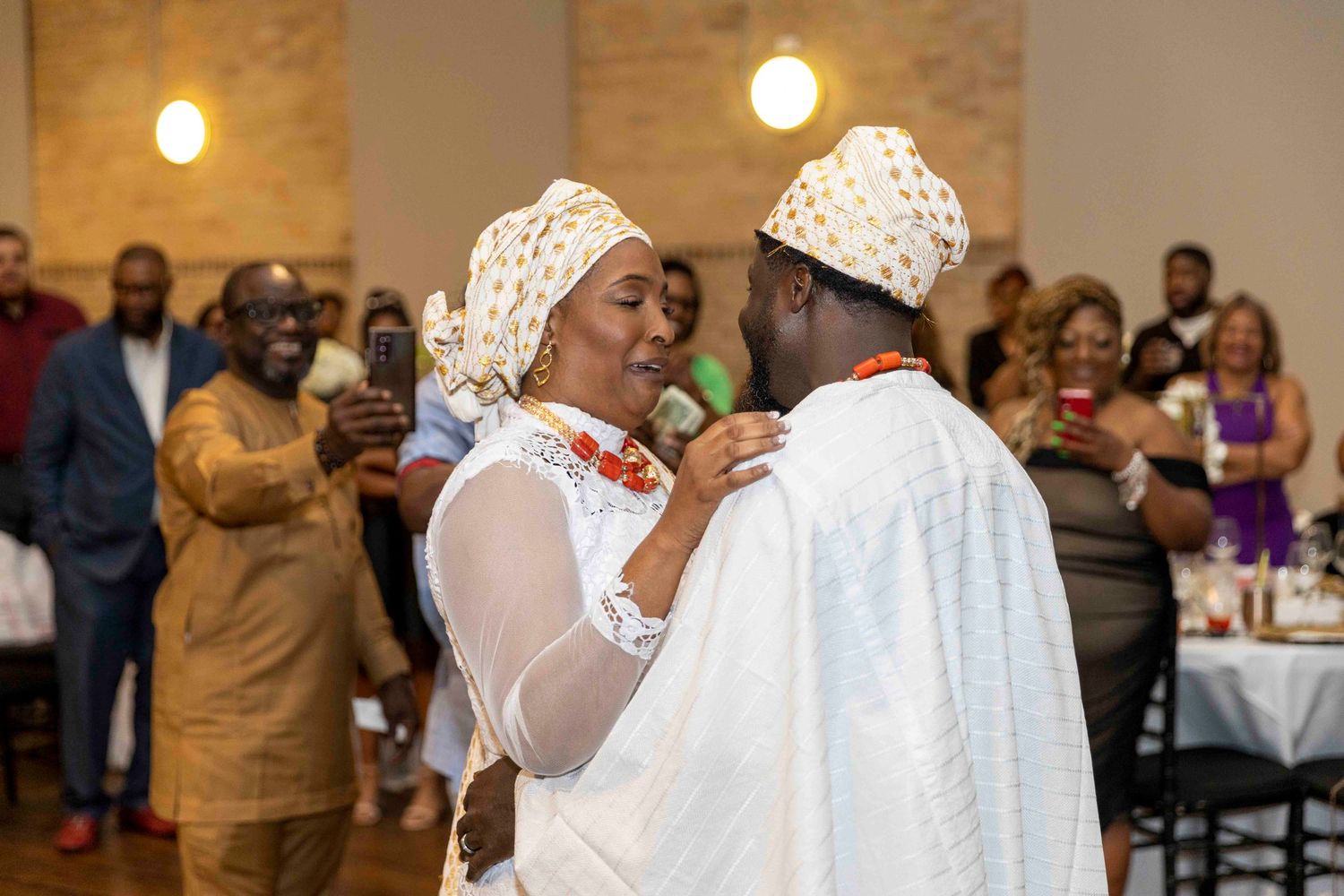 Guests enjoying themselves at an elegant indoor wedding reception with brick walls.