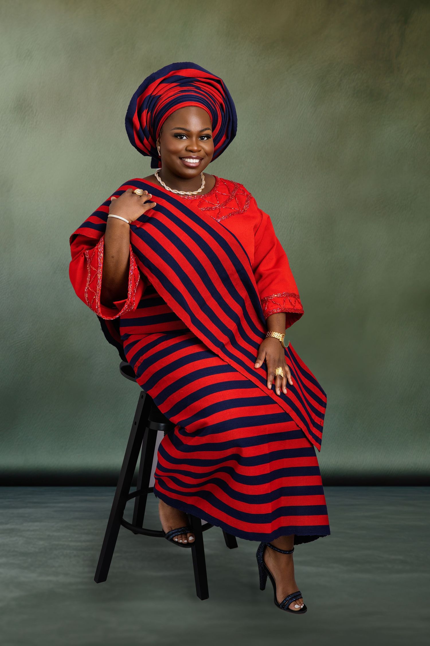 Elegant portraits in red and black striped traditional dress against green studio background.