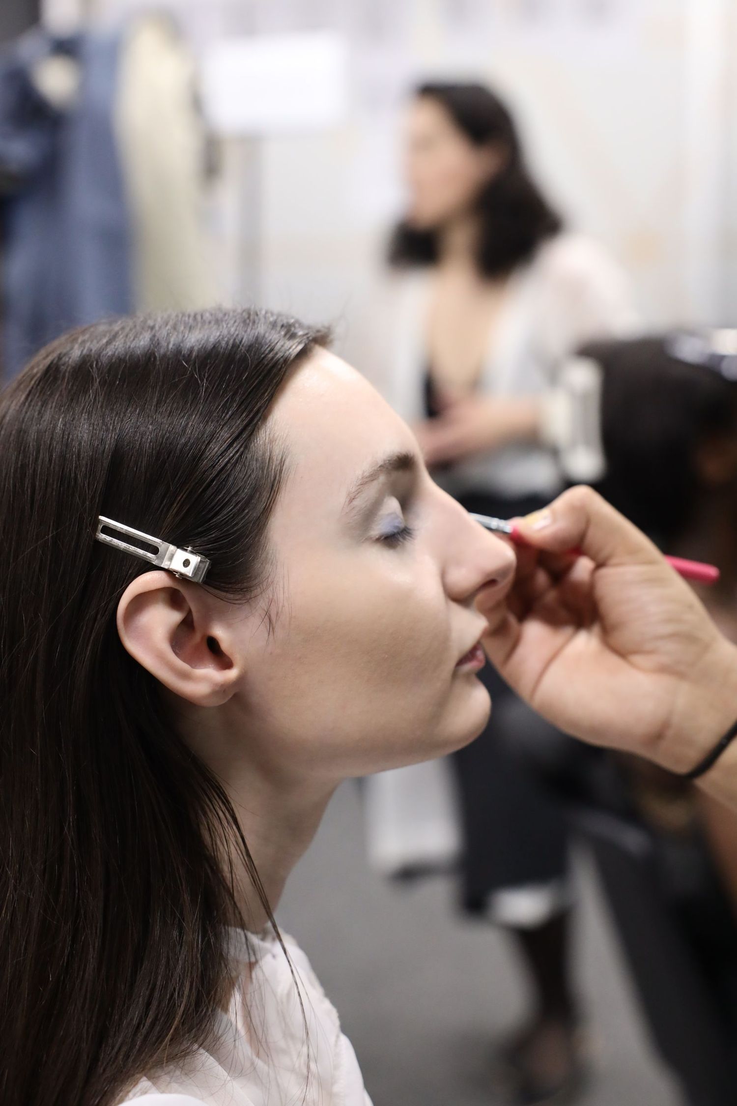 A makeup artist applies cosmetics to a model's face in a series of sequential photos showing the application process.