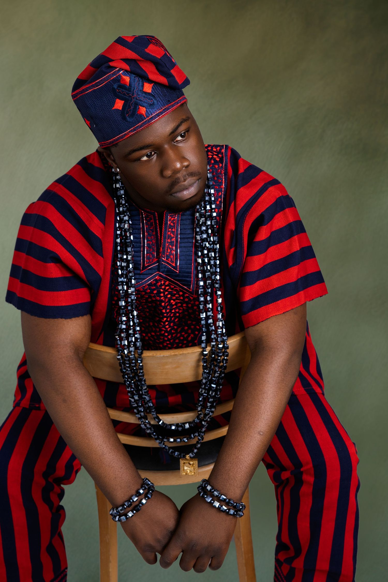 Studio portraits featuring red and navy striped traditional African clothing with beaded accessories.
