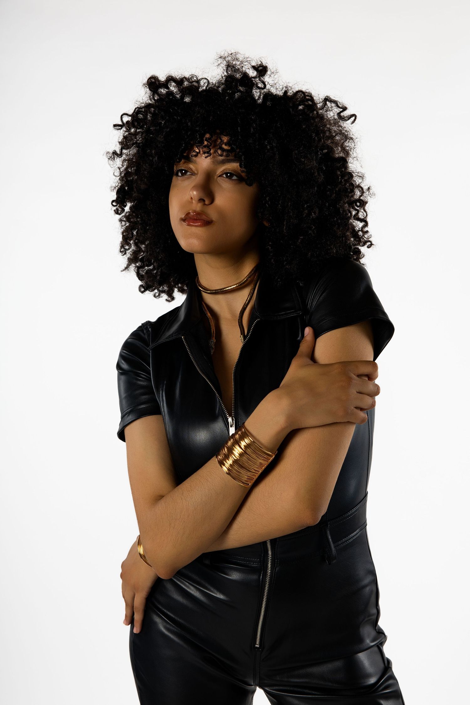 Studio portrait series featuring black leather outfit and natural curly hair against white backdrop.