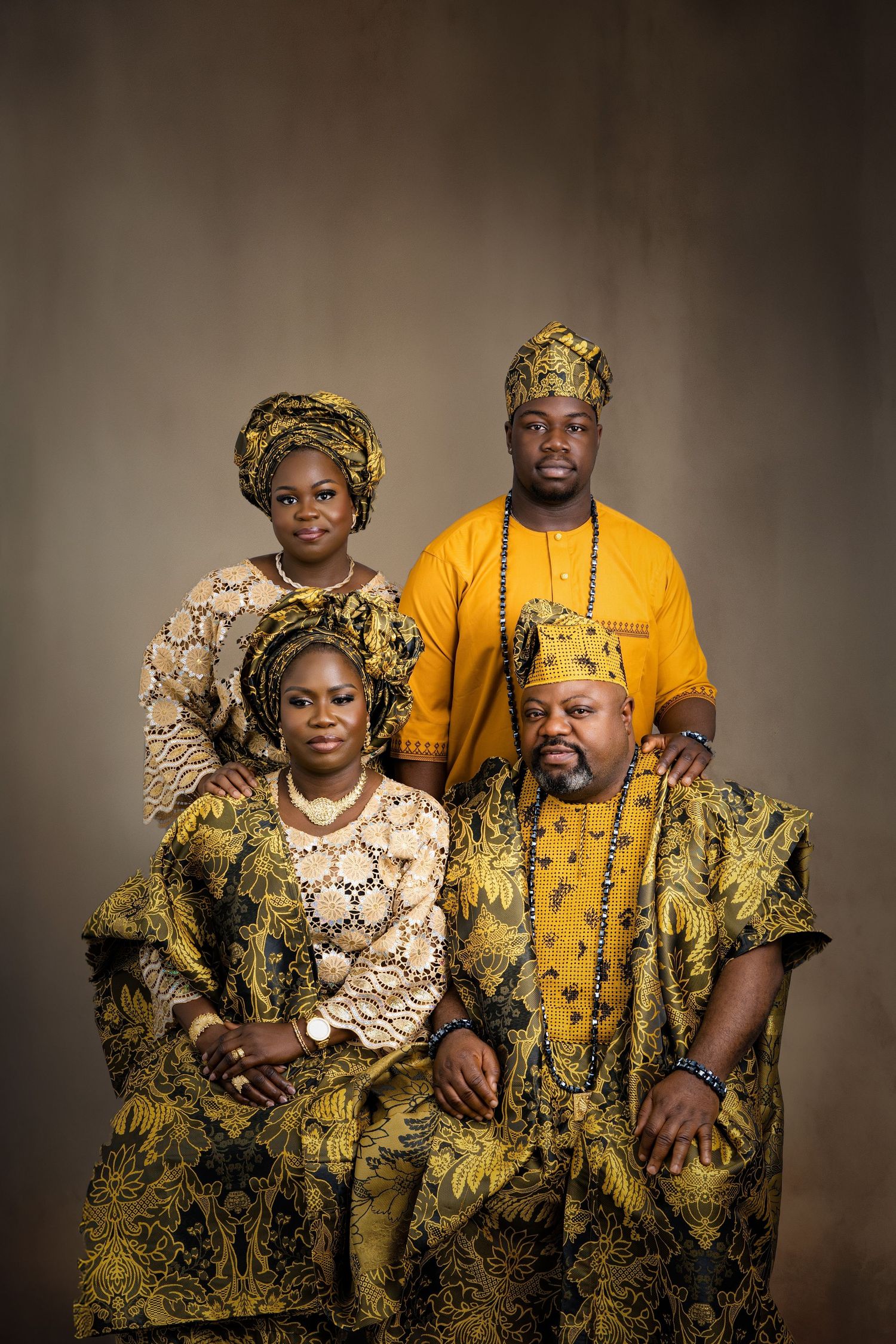 Family wearing traditional African attire in yellow and gold patterns for formal portrait.
