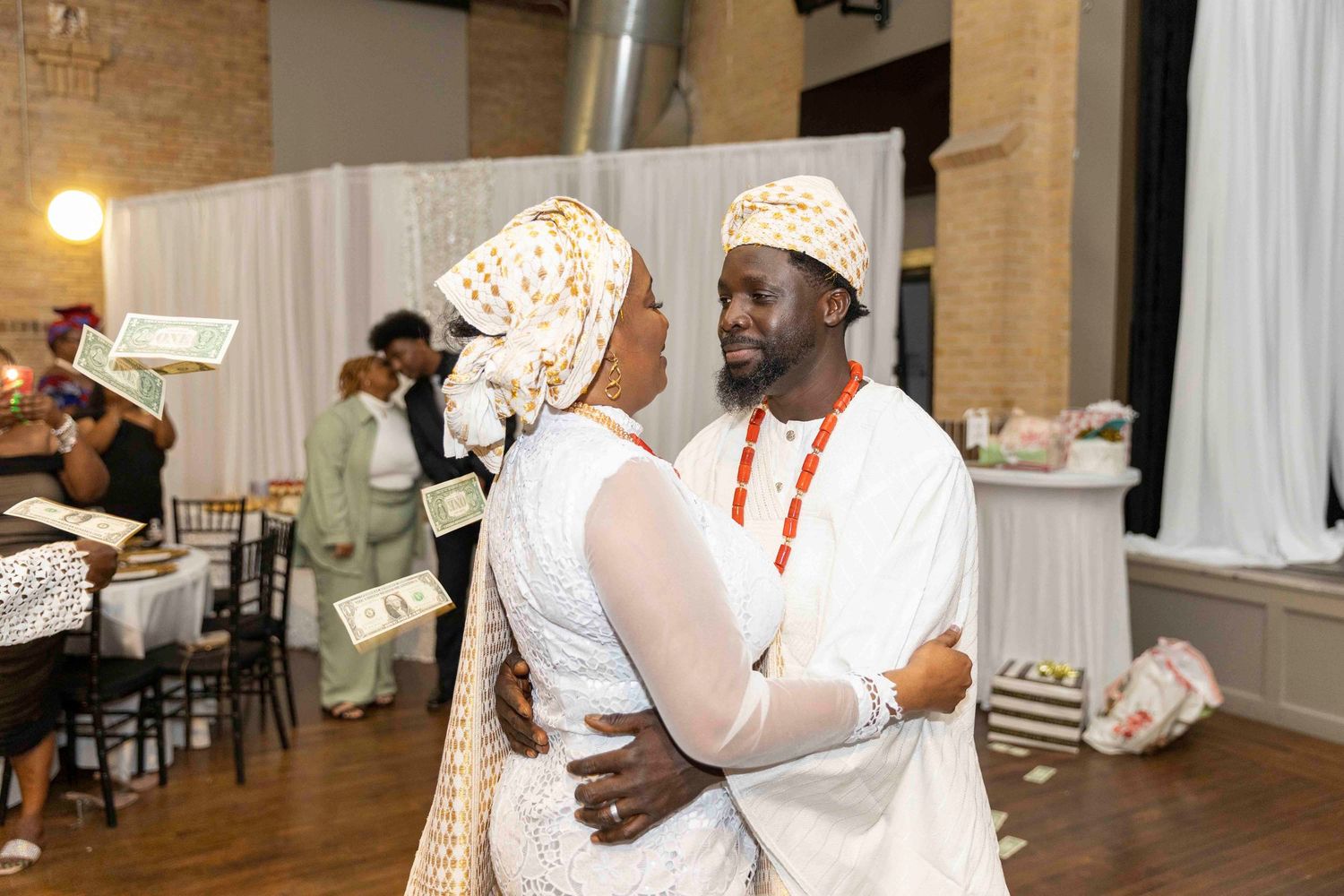 Wedding guests dancing and celebrating together at a reception with brick walls and warm lighting.