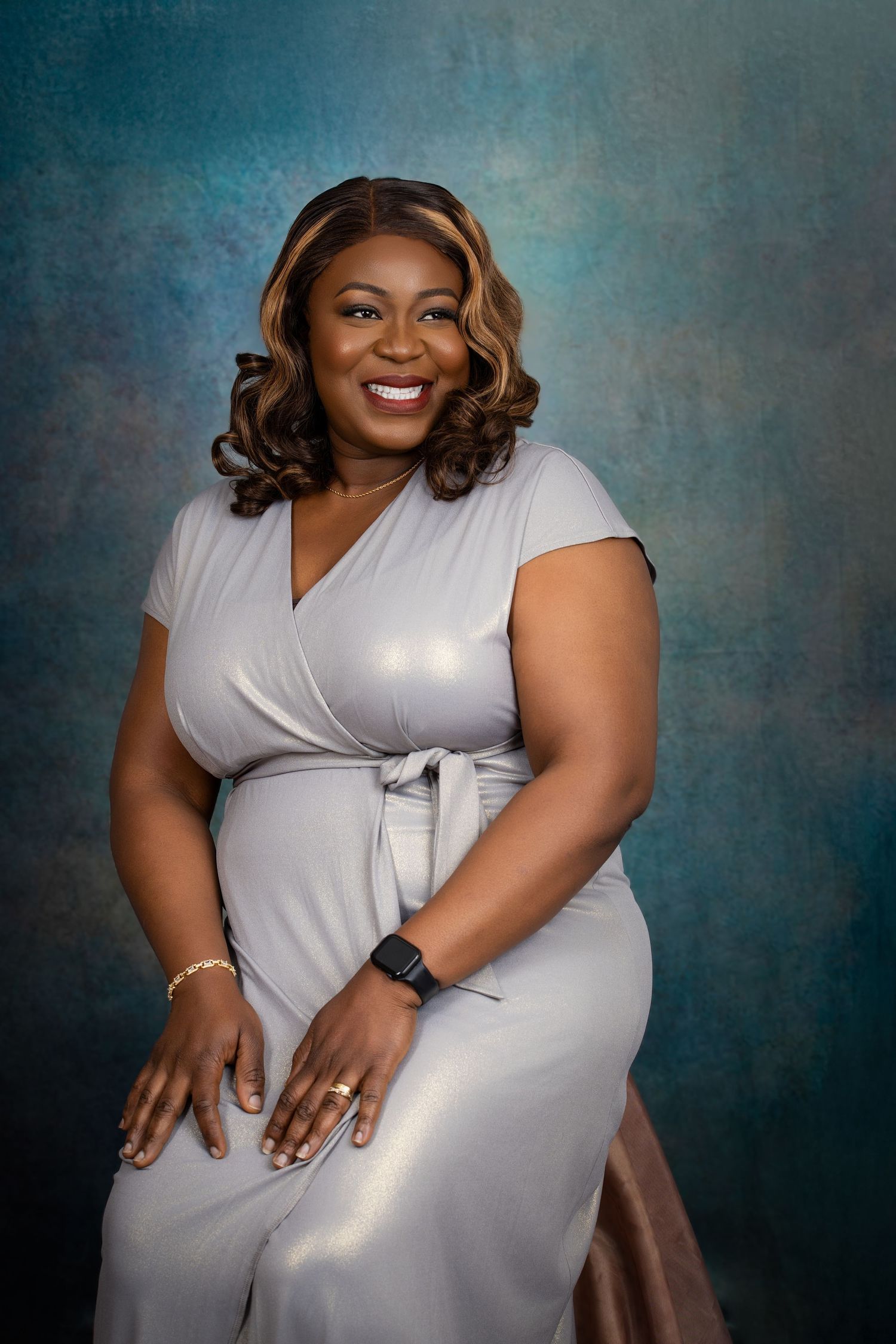 Professional portrait of a woman in a white wrap dress against a textured blue backdrop.