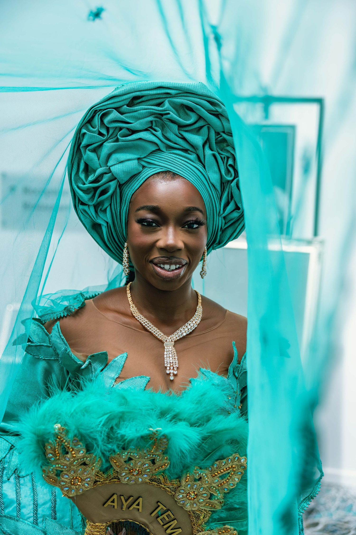 Elegant traditional attire featuring turquoise headwrap and gold embellished dress.