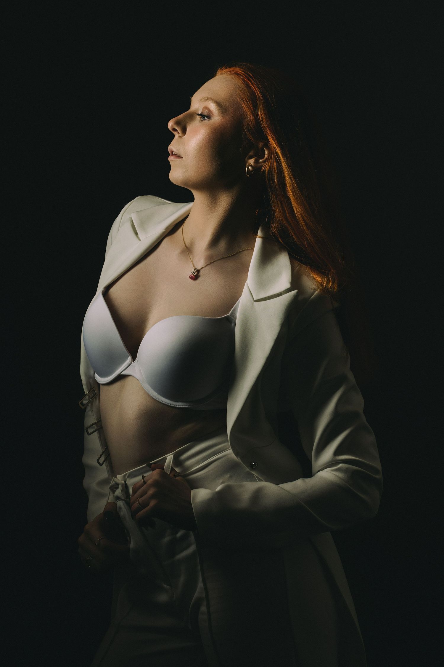 Artistic fashion portrait with white blazer in dramatic side lighting.
