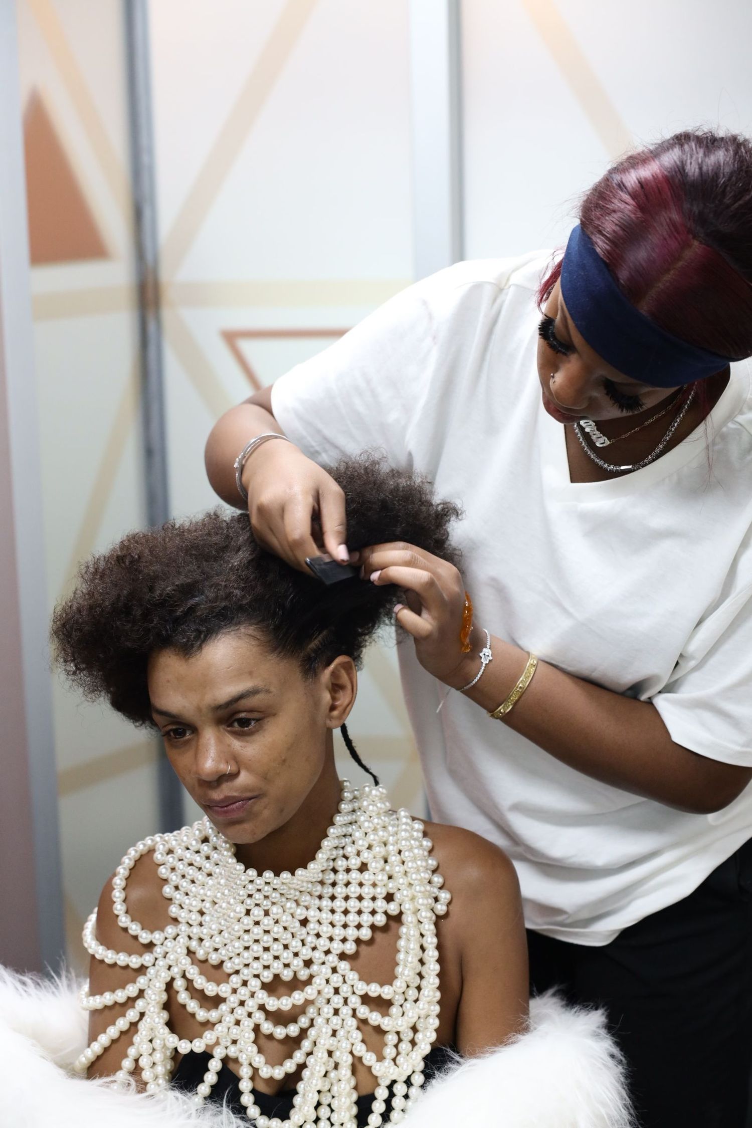 A hairstylist works on styling a model wearing an elegant pearl necklace in a progression of shots.