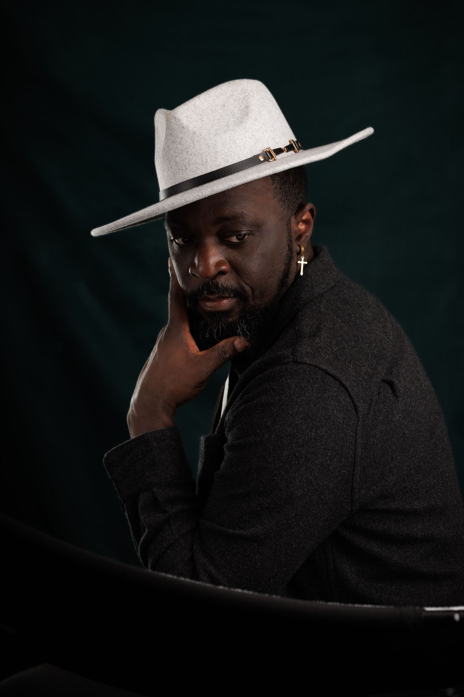 Moody portrait series featuring a light fedora hat and dark jacket against a black background.