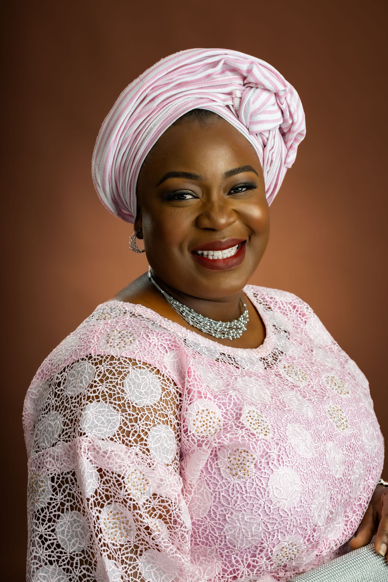 Traditional portrait in pink lace dress and head wrap with statement necklace.