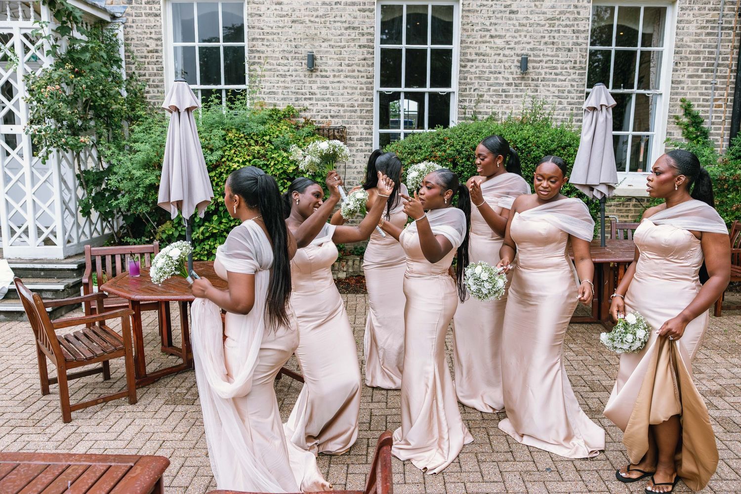 Bridesmaids in pink dresses posing together outside historic building.
