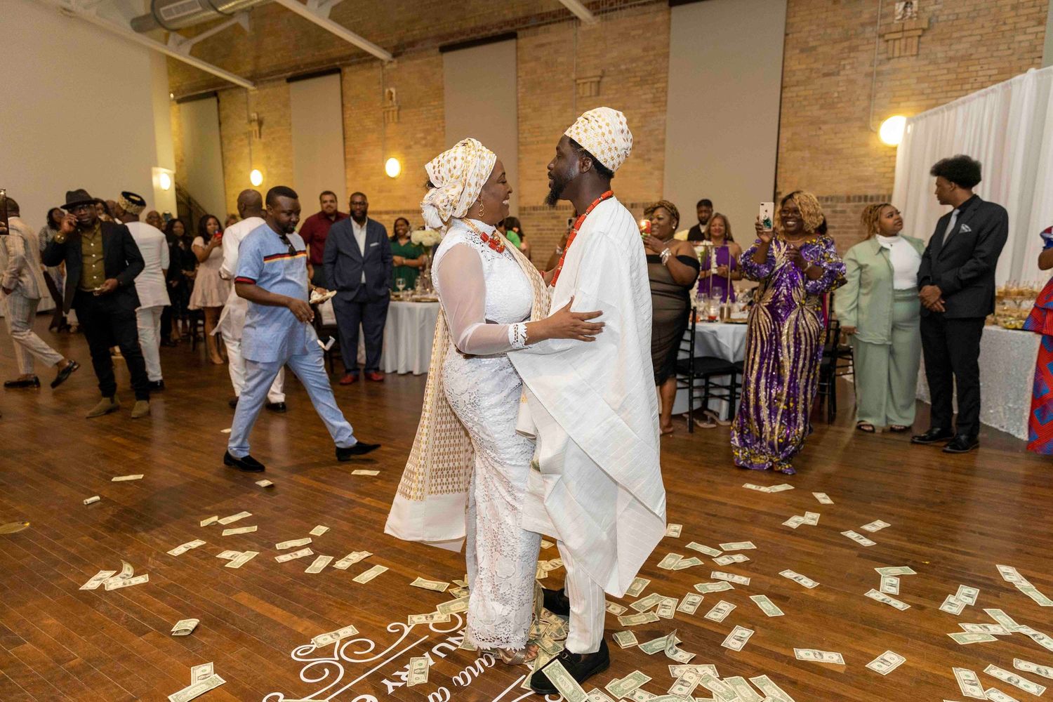 Traditional celebration with guests in white attire dancing on a petal-covered floor.