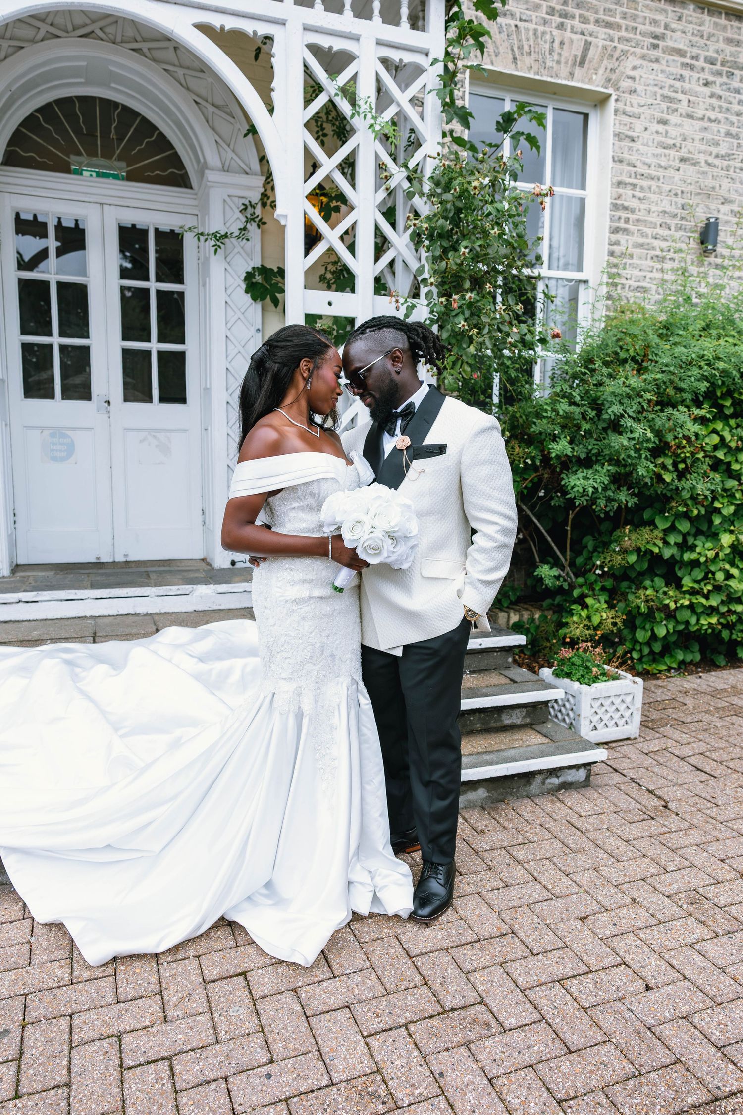 Wedding photo series showing couple in white dress and tux dancing outside brick building.