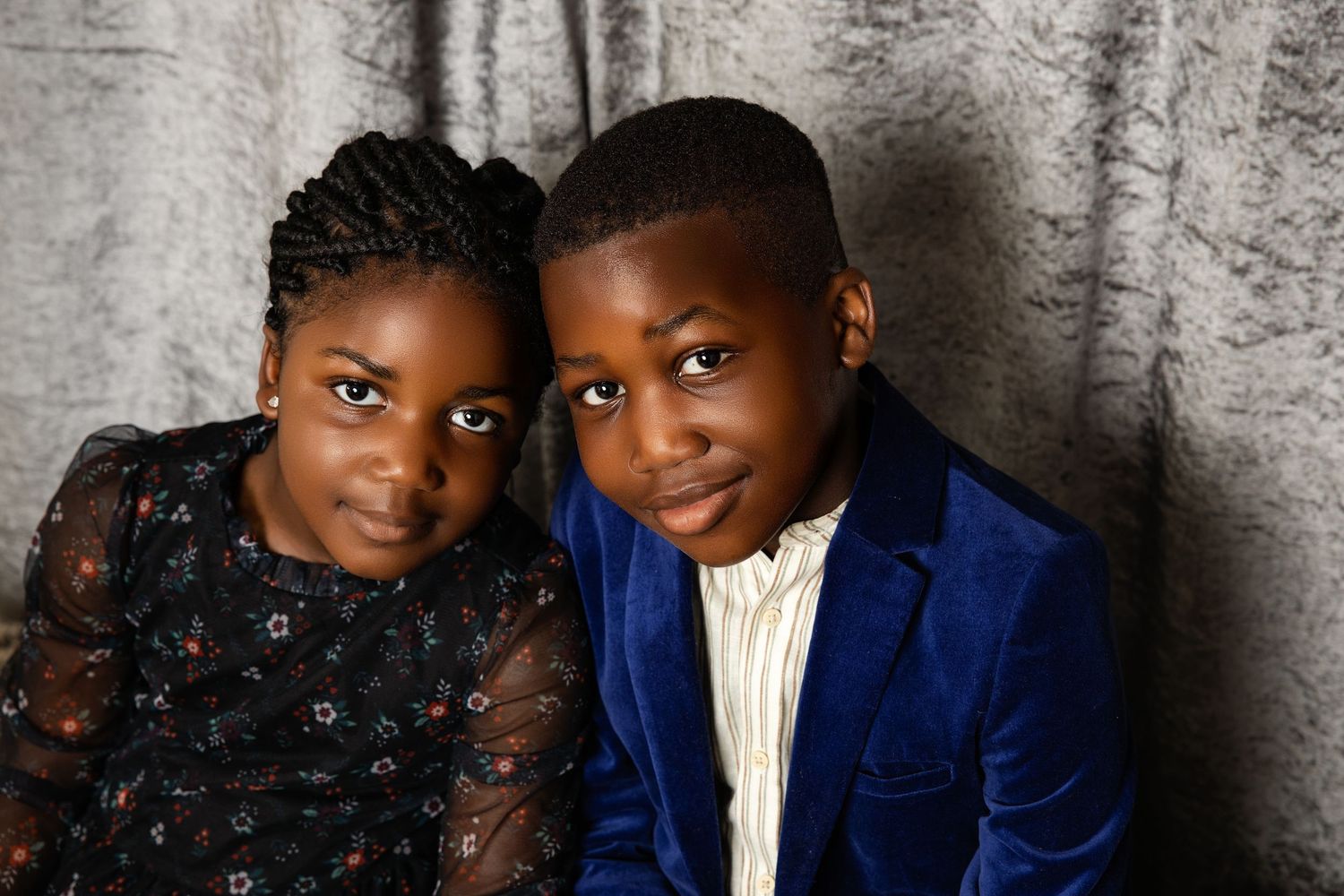 A family portrait featuring coordinated blue and black outfits against a textured wall.