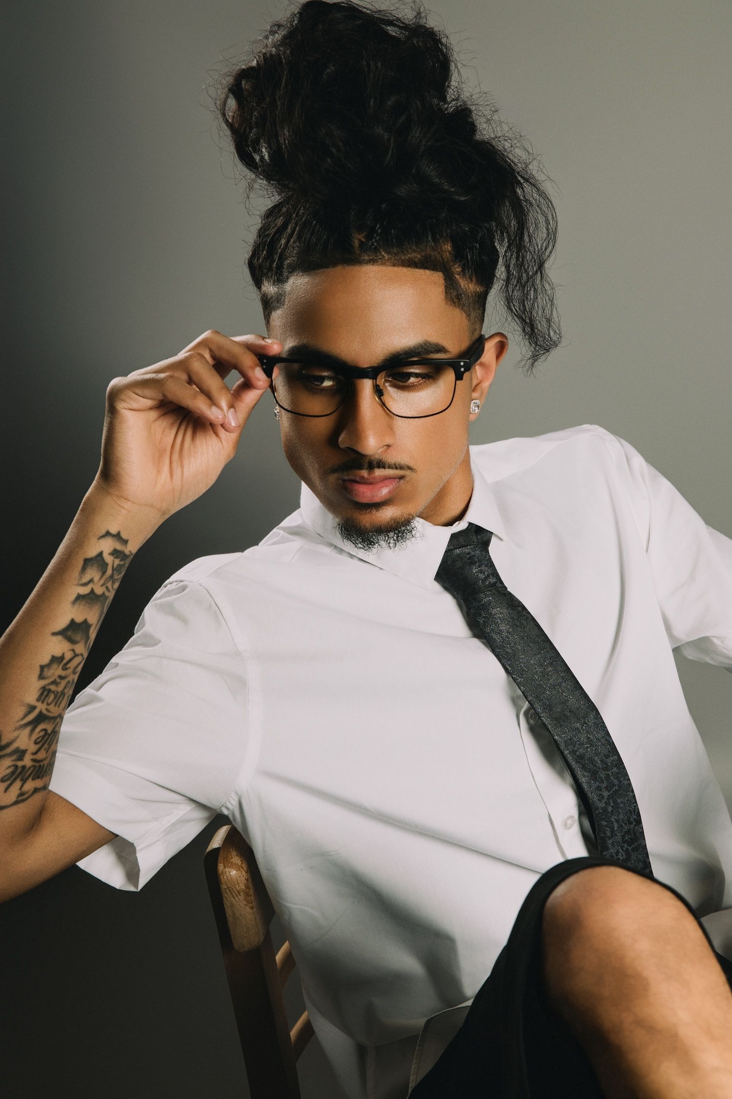 A series of moody portraits showing someone in a white shirt and black tie adjusting their glasses against a dark background.