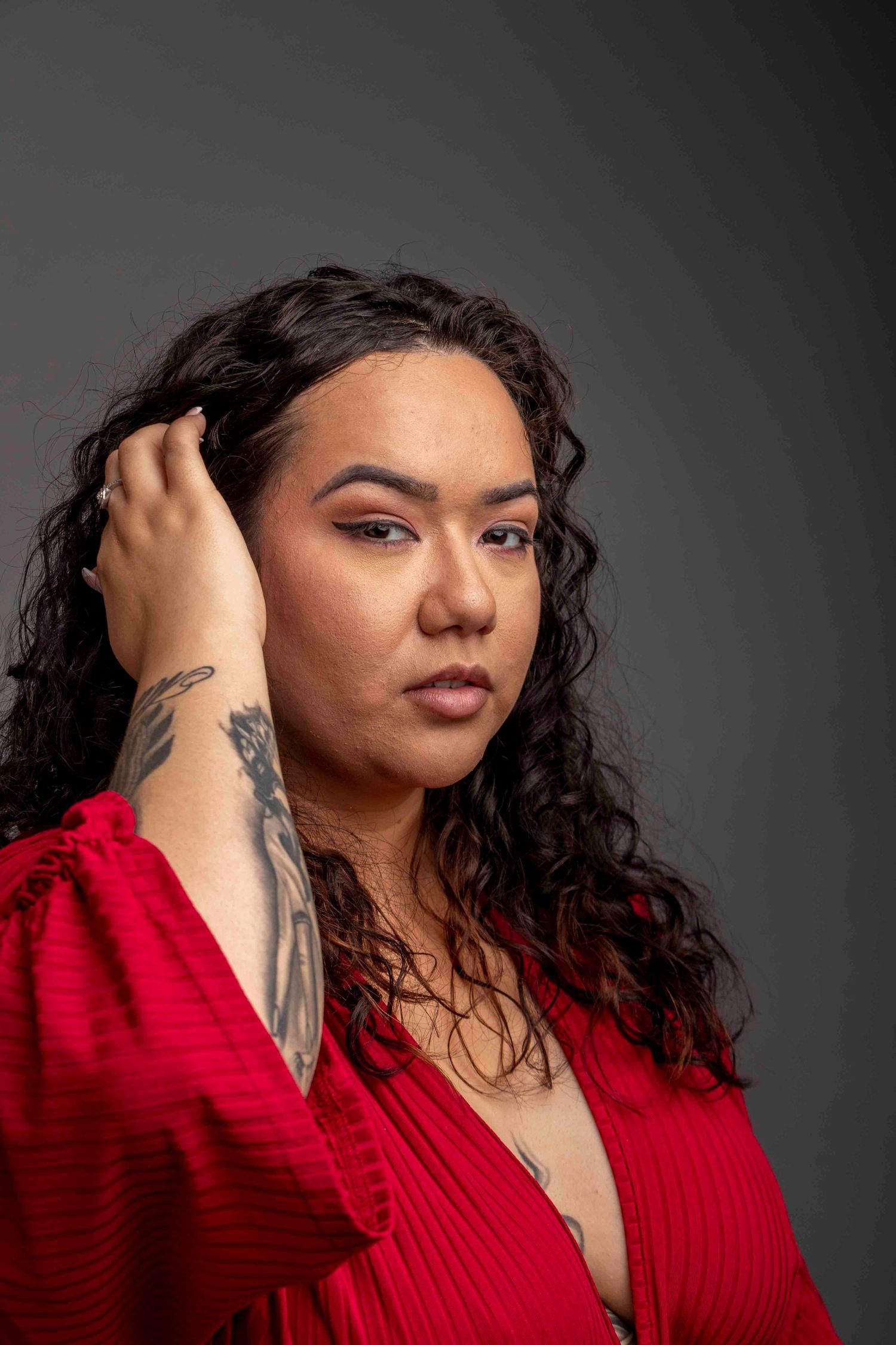 Artistic portrait series of a person in a red top with curly hair against a dark background.