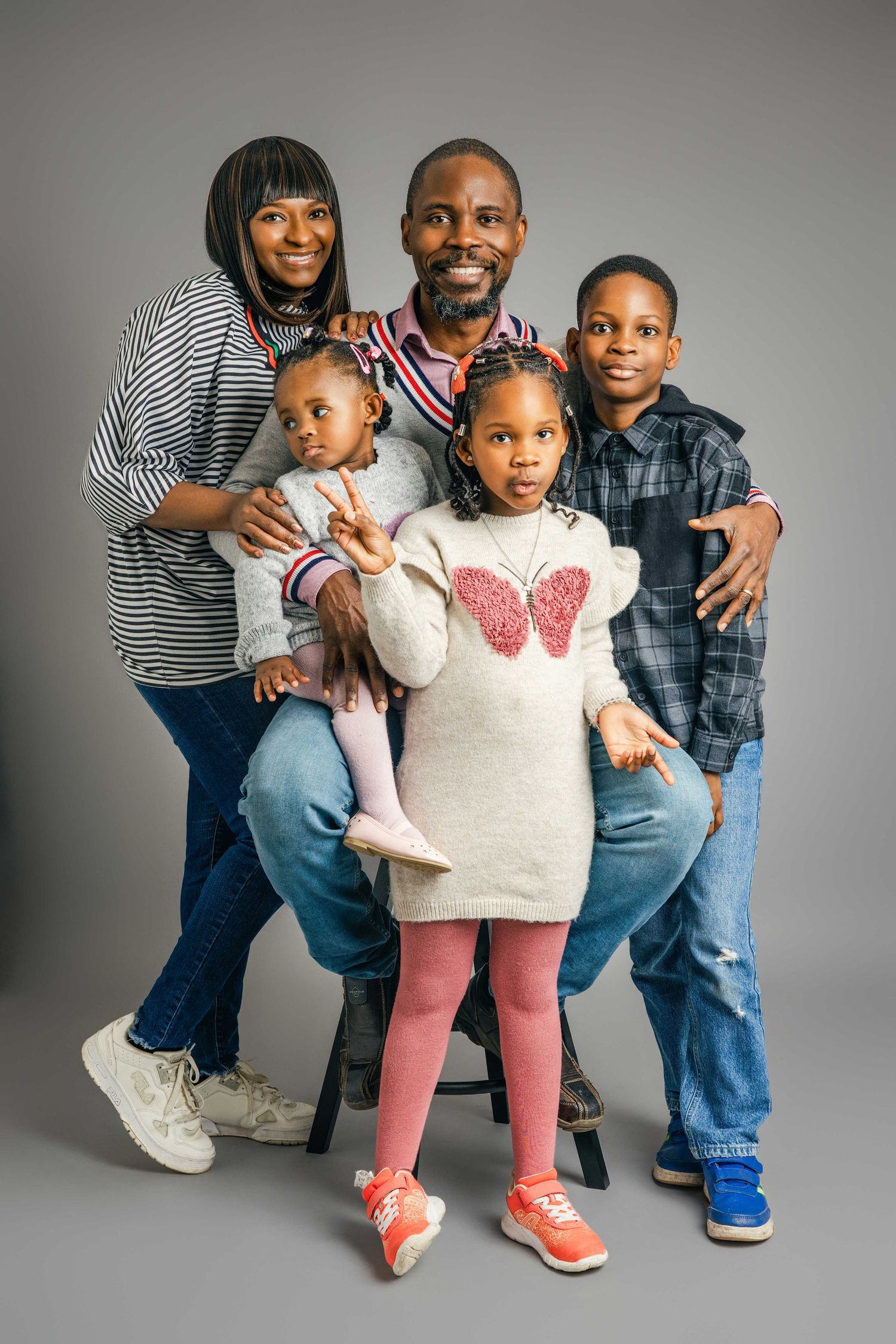 Family of four posing together in coordinated casual outfits during studio photoshoot.