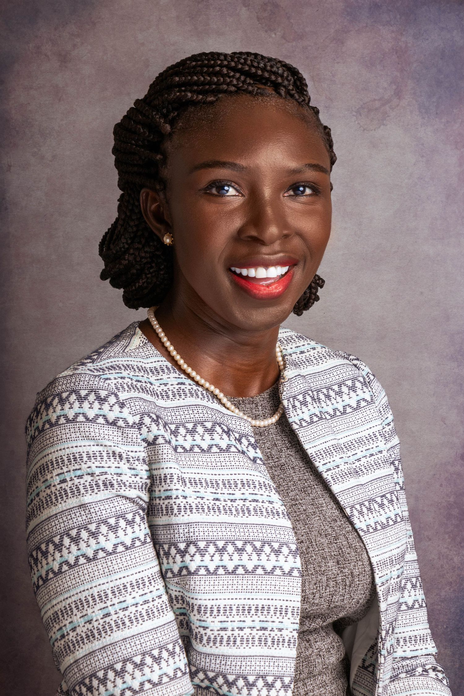 Professional wearing patterned white jacket and braided hairstyle in studio portrait.