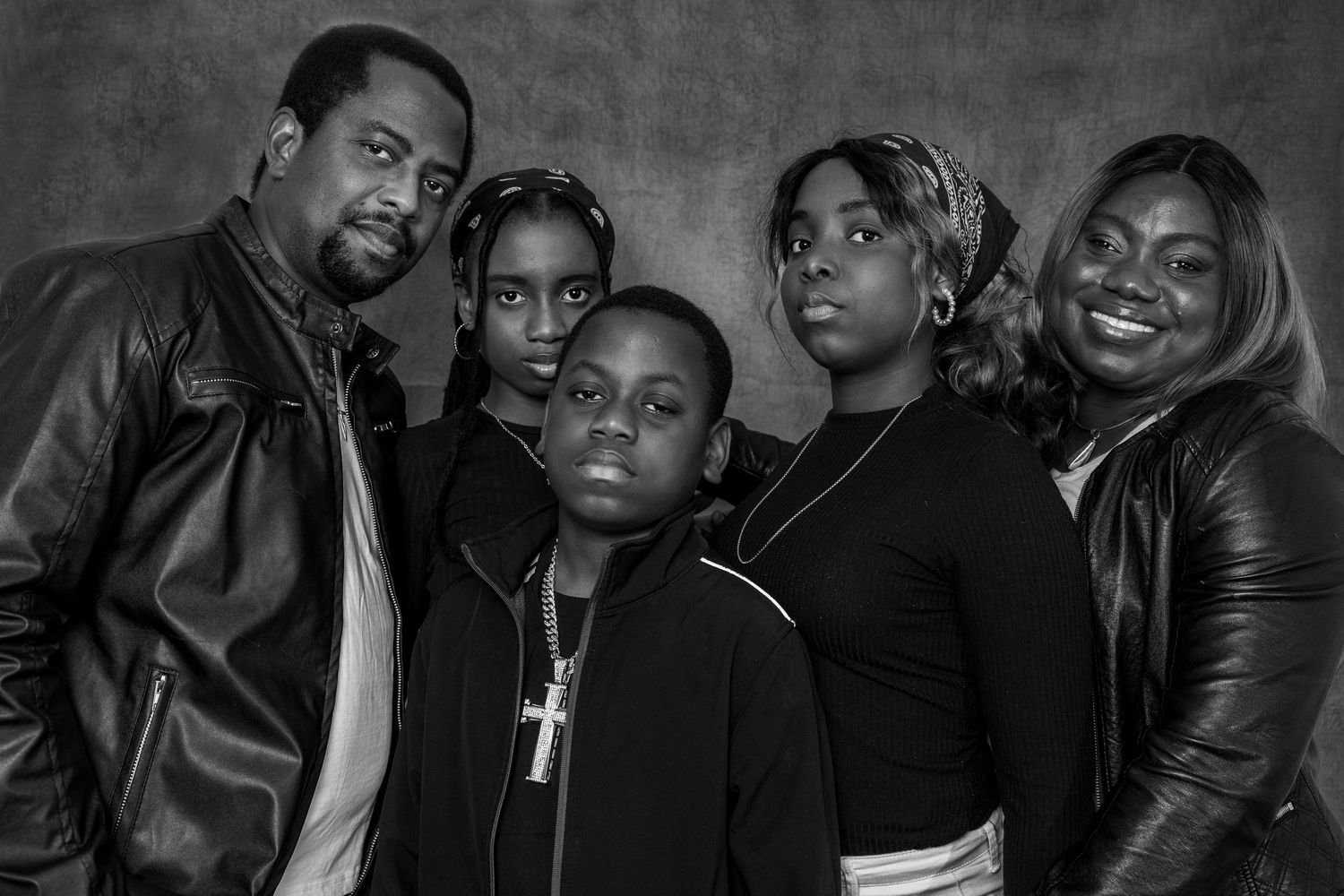 A family group poses in black leather jackets for a moody studio portrait.