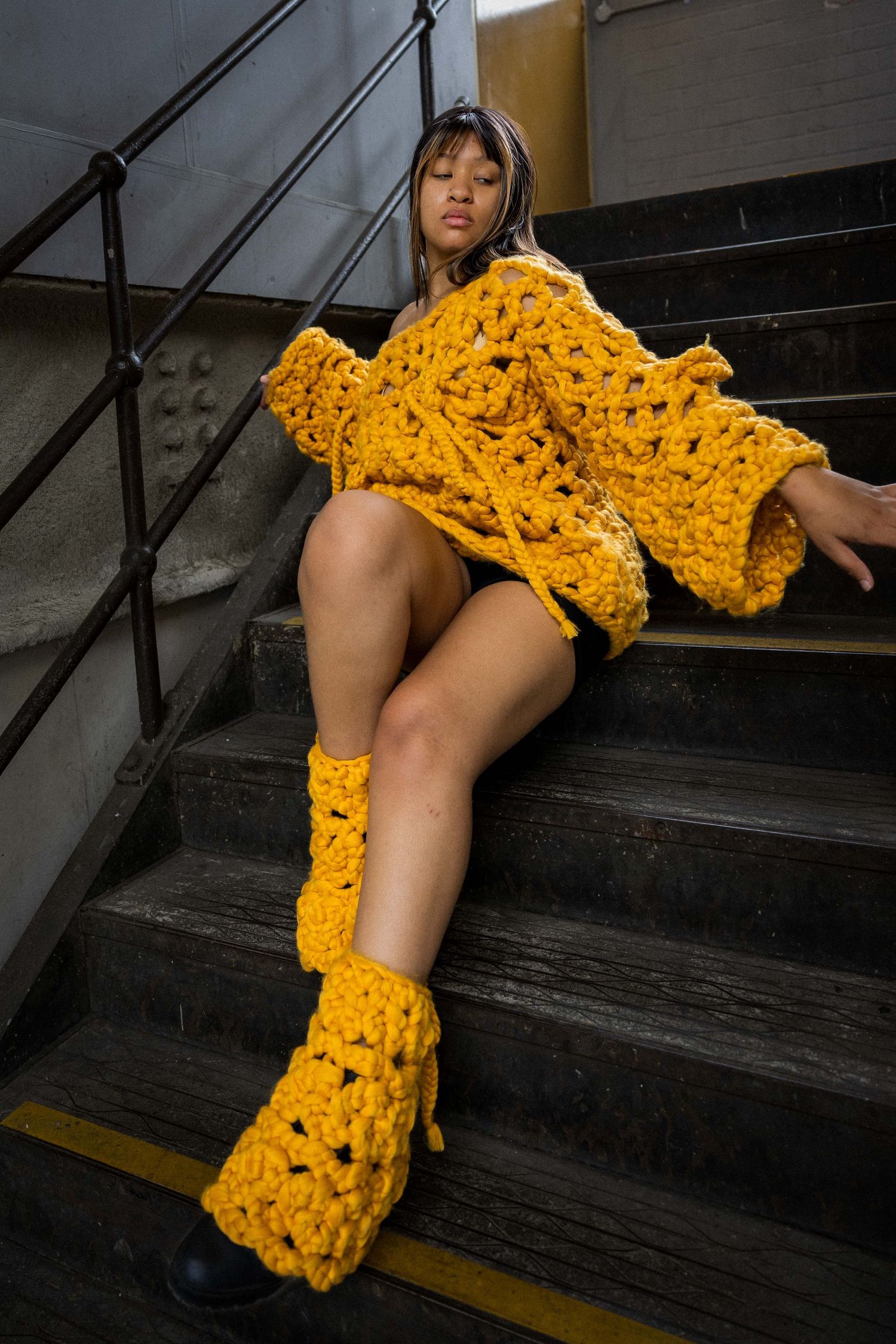 Artistic fashion photo on stairs with bright yellow crochet dress and matching leg warmers.