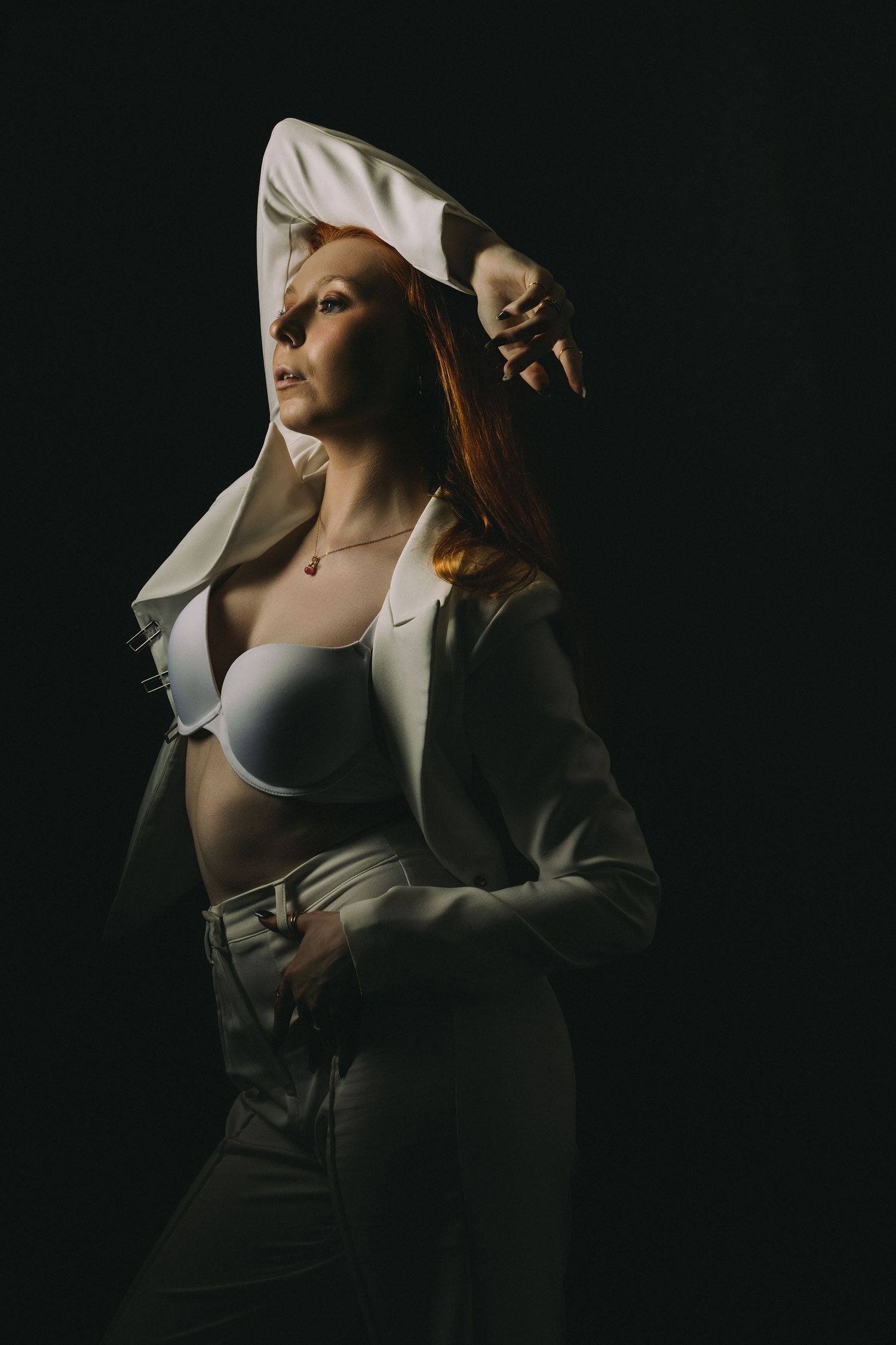 Dramatic low-key portrait in beige blazer with moody lighting.
