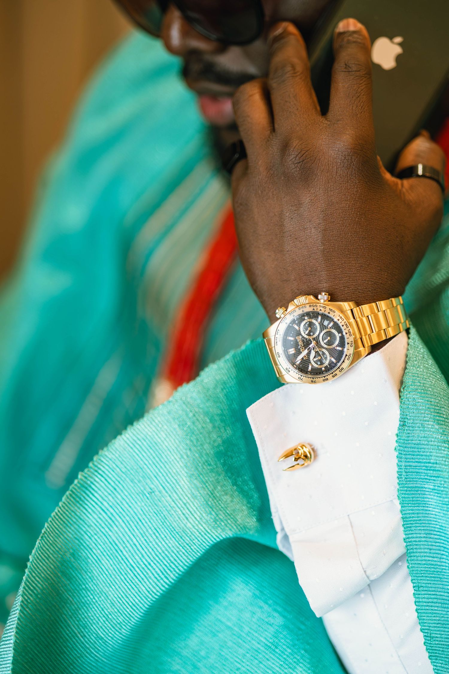 Close-up detail of turquoise fabric and gold watch accessories.