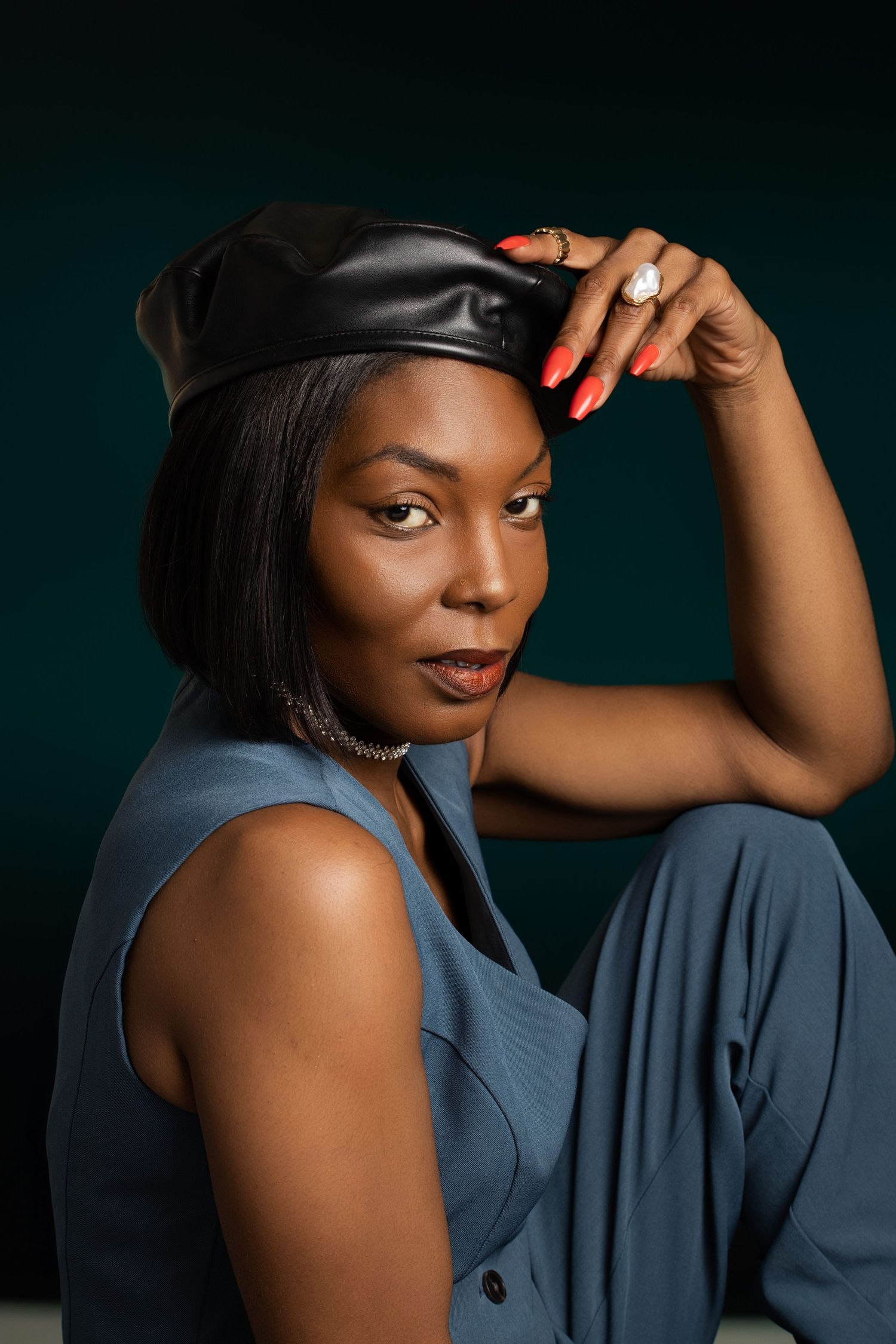 Fashion portrait series in blue attire with a cap against a dark dramatic background.