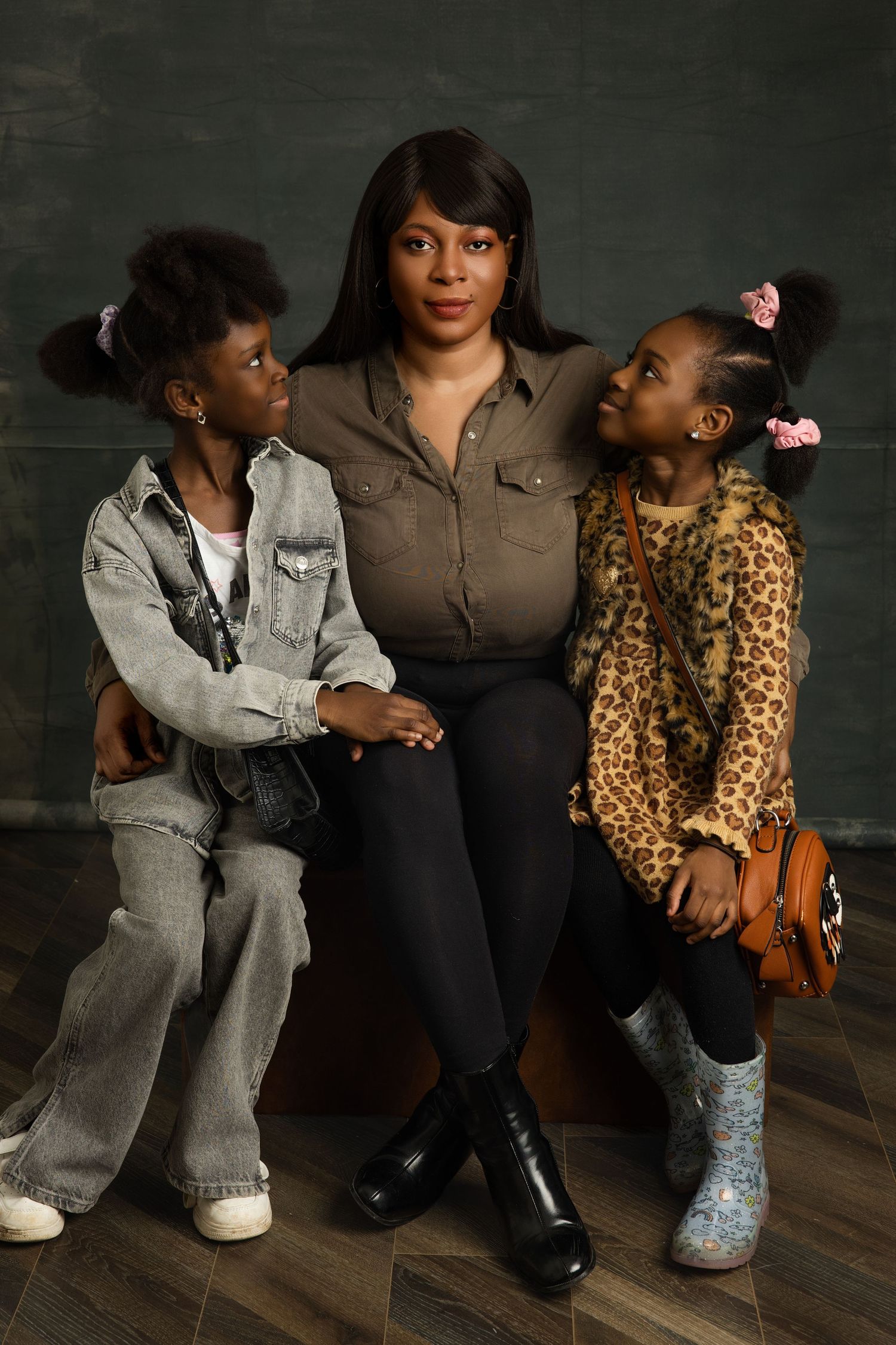 Three people sit casually on the floor wearing contrasting outfits of denim, black, and leopard print.