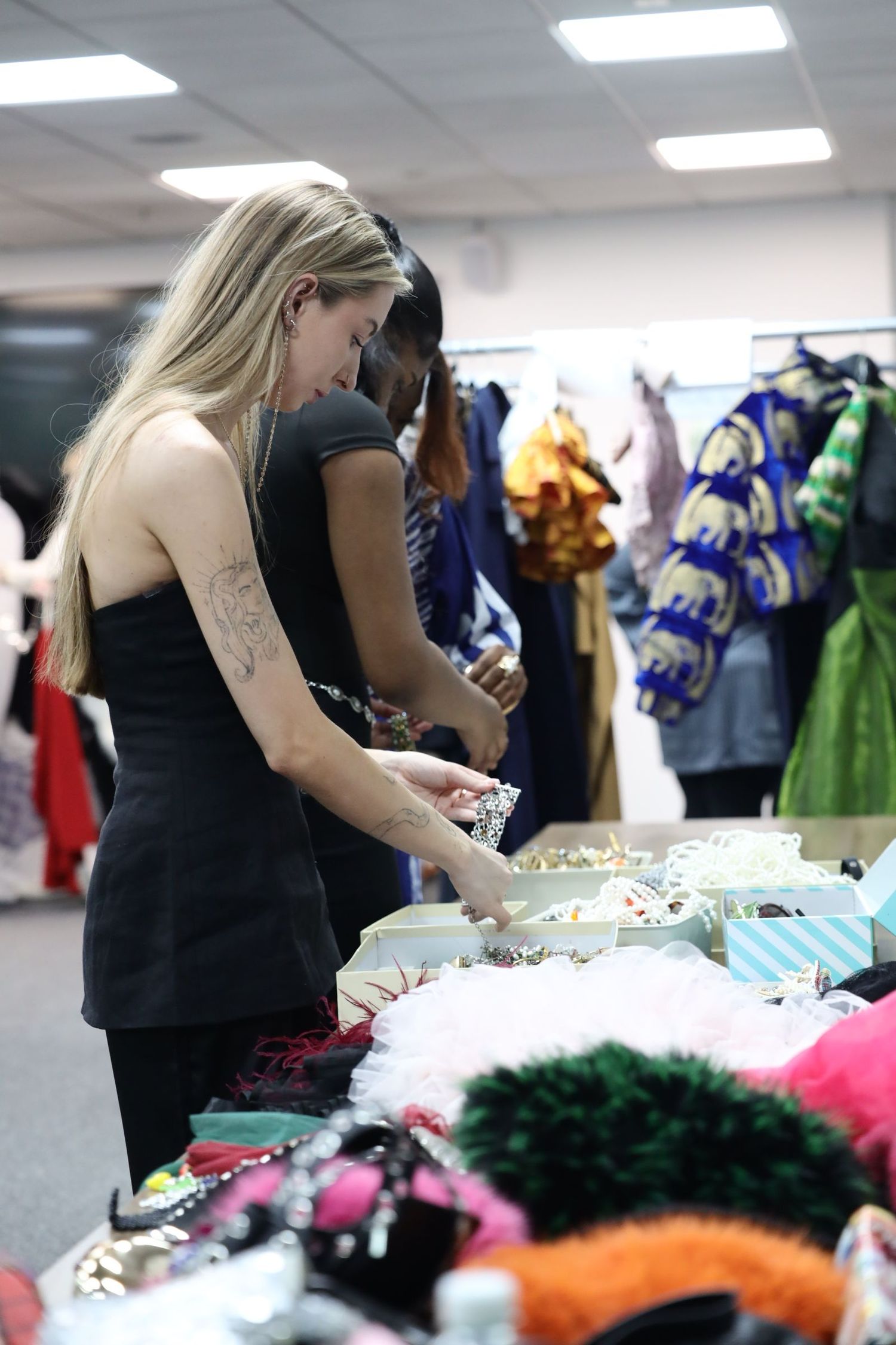 People browse through colorful costumes and accessories at a wardrobe or costume shop display.