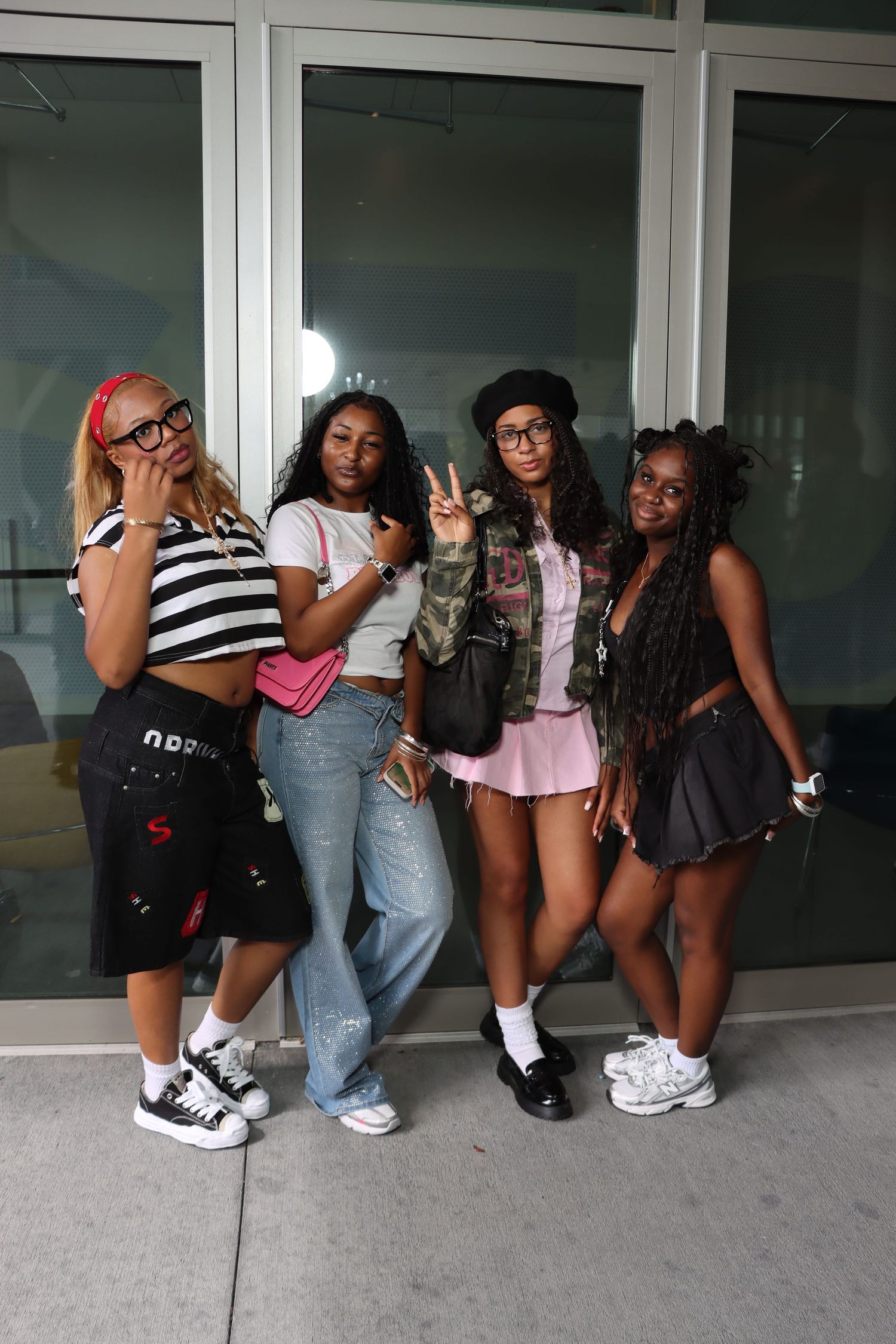 A group of friends pose together in a creative line formation against a wall, wearing casual streetwear outfits.