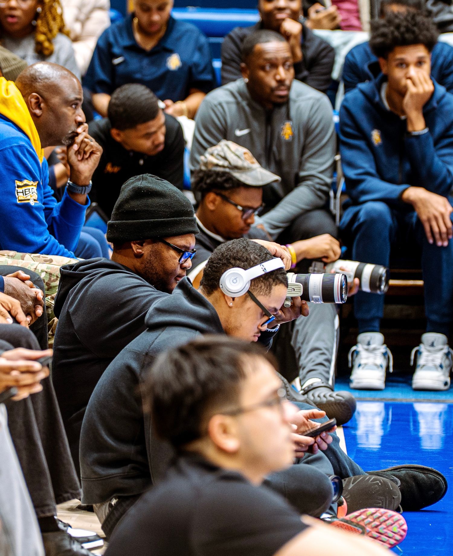 People sit in rows watching intently at what appears to be a sporting event or presentation.